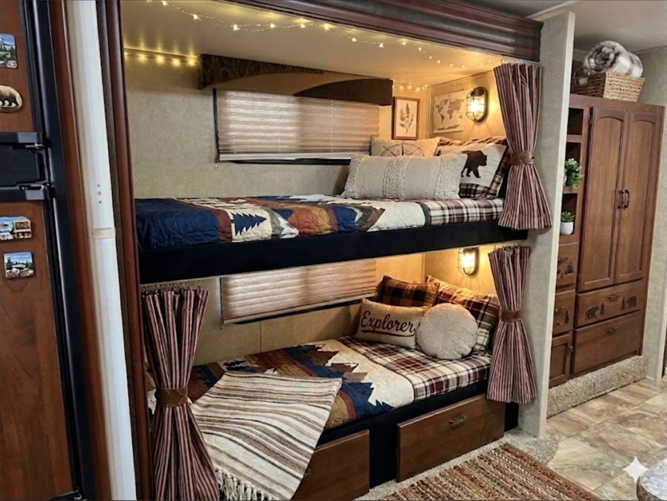 This cozy rv rental bunkhouse features rustic plaid bedding, string lights, and curtains, perfect for family travel adventures.. Jayco Redhawk 2014