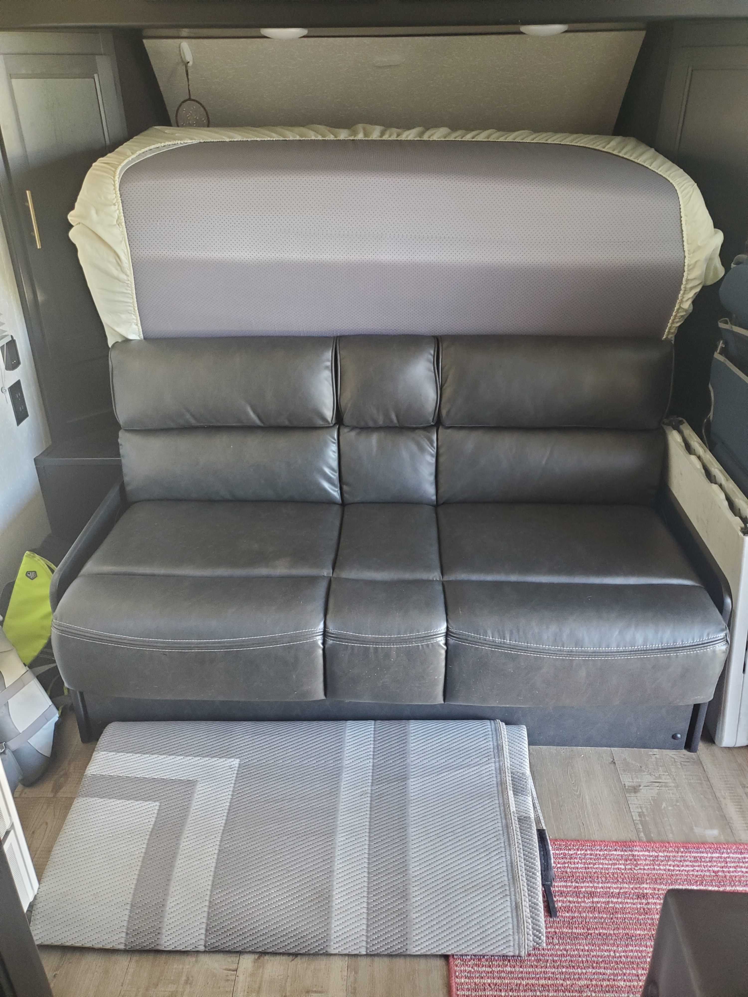 RV rental: Dark gray sofa beneath a ready-made bed, with floor rugs. A cozy, compact living area for travelers.. Forest River Cherokee Wolf Pup 2022