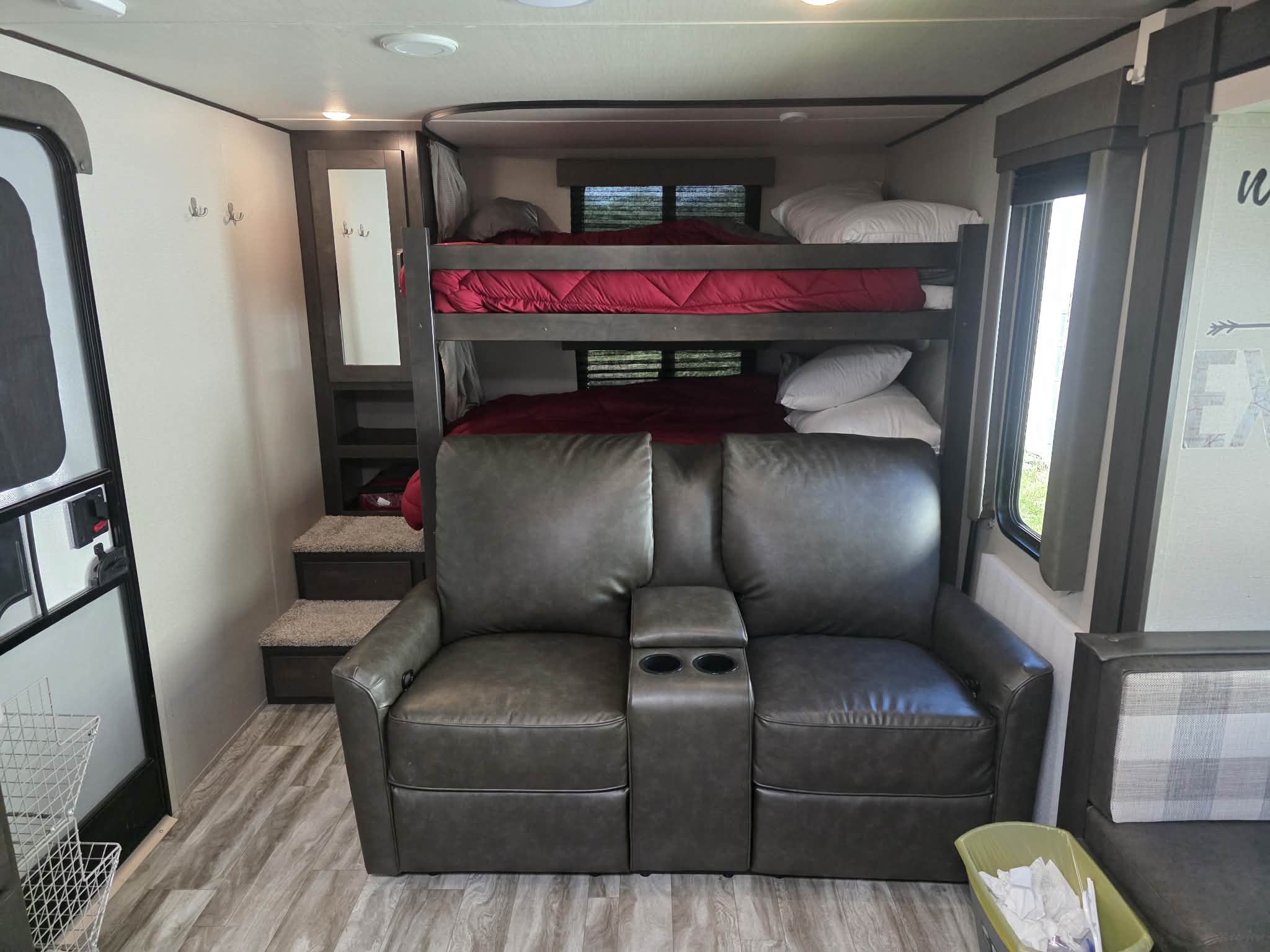 RV rental interior with cozy bunk beds, a two-seater reclining sofa, and an entry door.. Grand Design Transcend Xplor 2021