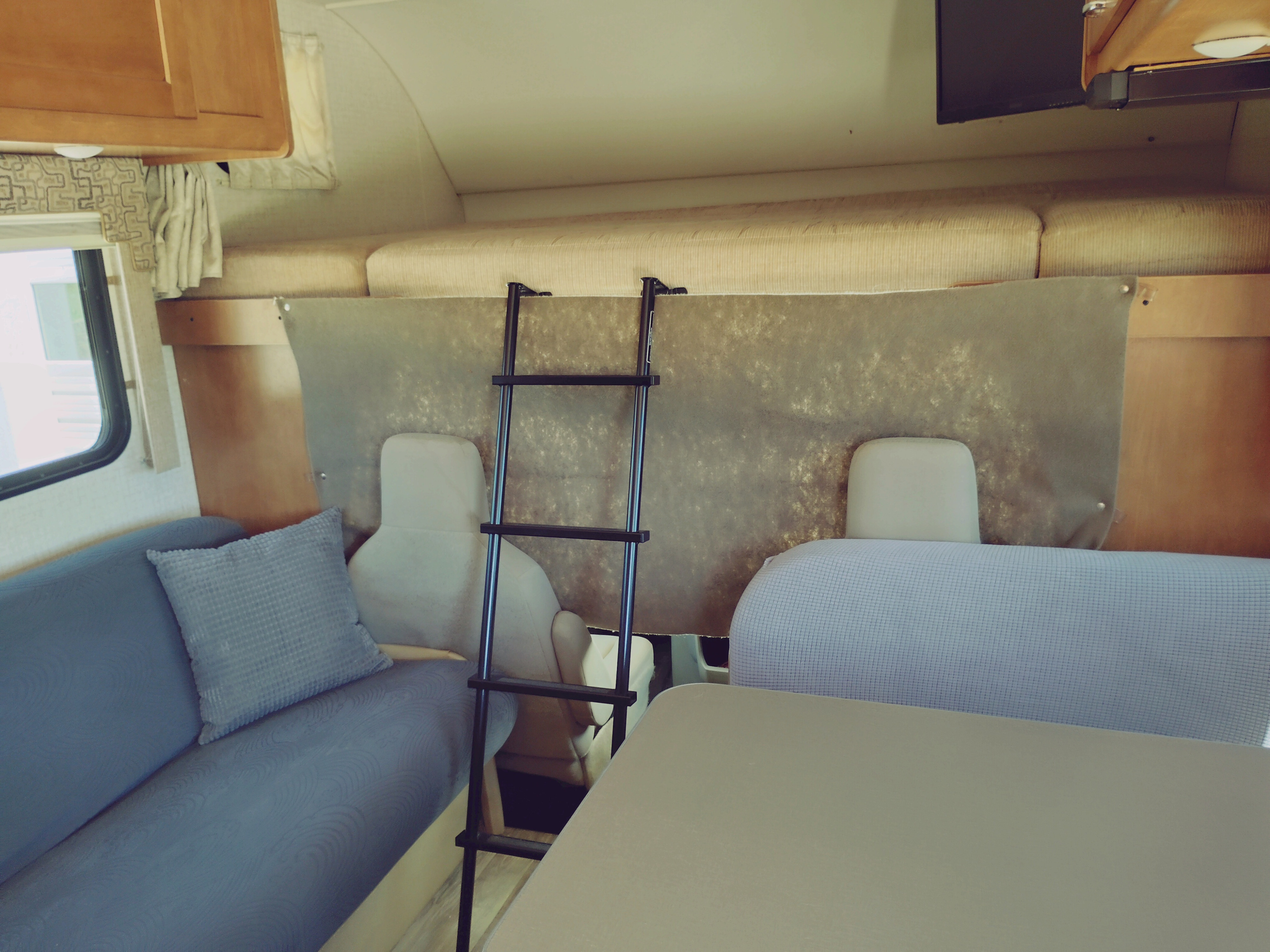 Cozy RV rental interior showing a bunk bed with ladder, blue couch, and dining table. Perfect for family travel.. Winnebago Minnie Winnie 2017