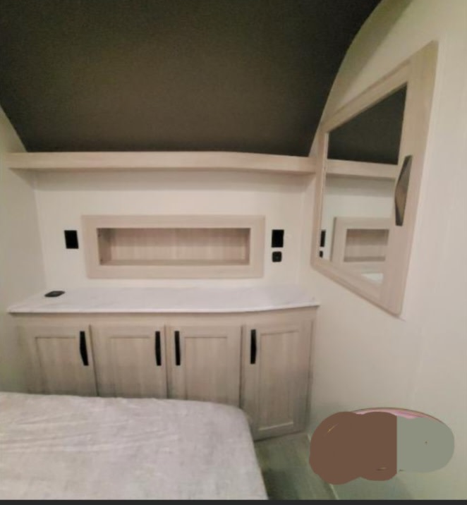 This RV rental's bedroom offers a bed, integrated headboard storage, lower cabinets, and a corner mirror for a compact, functional space.. Cruiser Rv Corp Stryker 2025