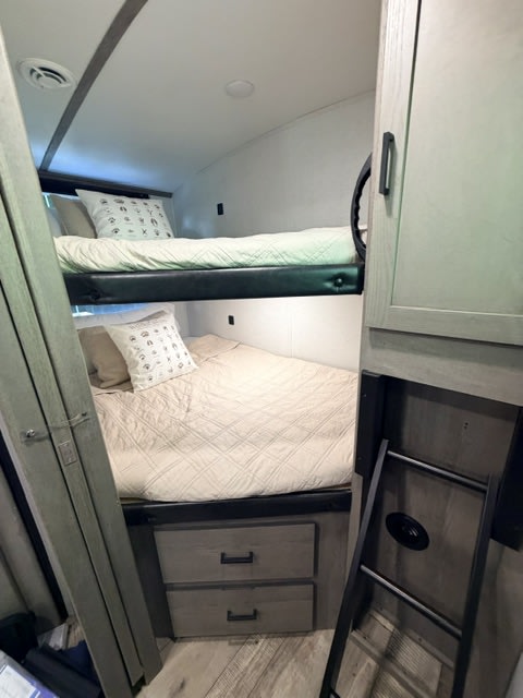 Inside this cozy rv rental, discover bunk beds with storage drawers below and a ladder for access. Modern camper interior.. Keystone RV Outback Ultra-Lite 2021