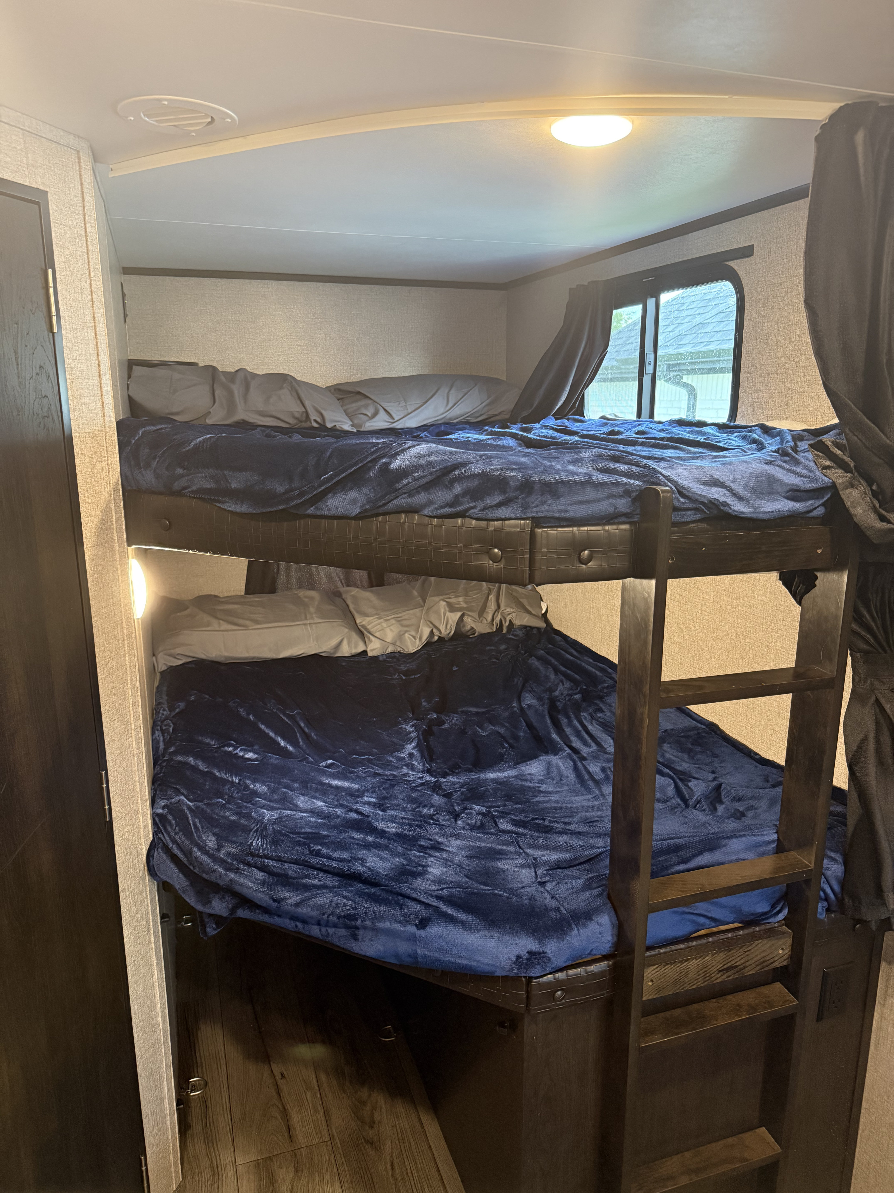 Inside an RV rental: two bunk beds with blue blankets, gray pillows, and a small ladder, offering a cozy sleeping space.. Jayco Jay Feather 2021