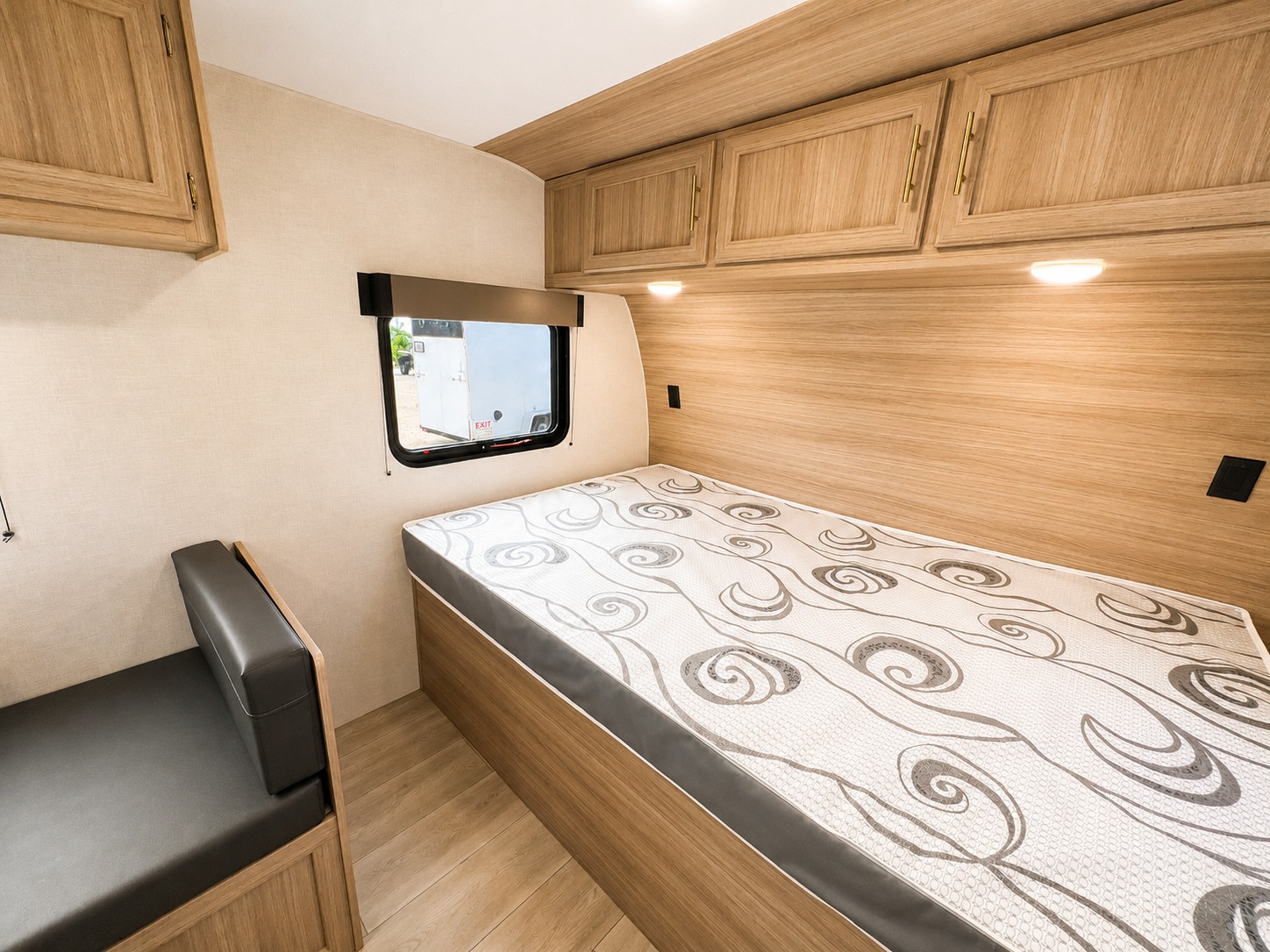 This RV rental offers a compact and functional bedroom with a single bed, overhead cabinets, and a side bench seat.. KZ Sportsmen Classic 2025