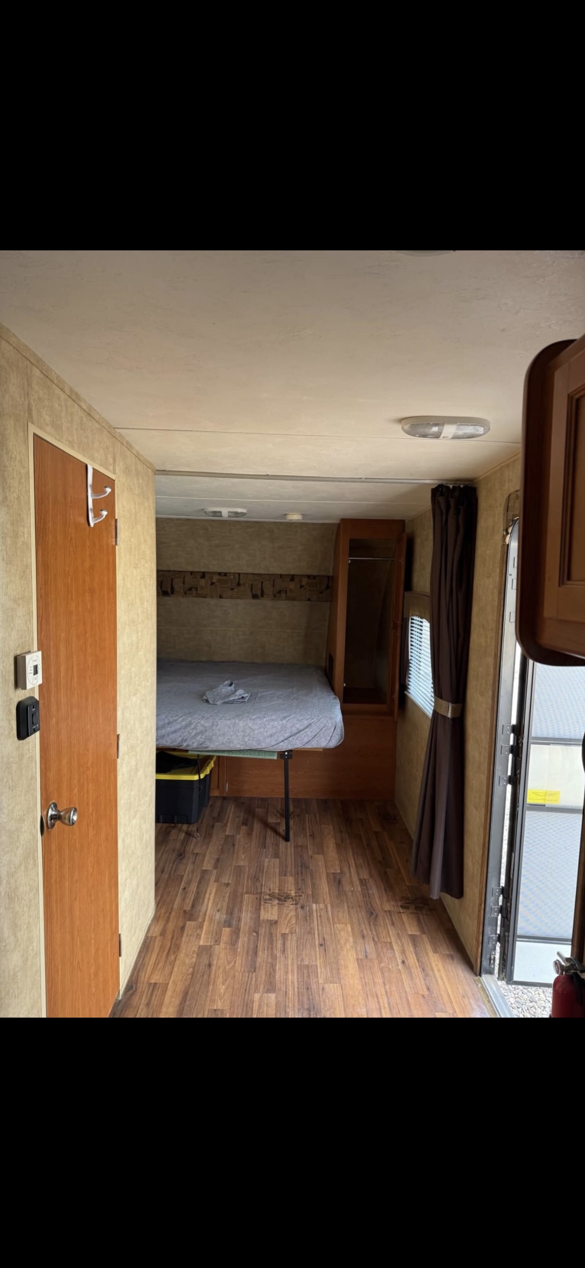Experience comfort in this RV rental! Interior shows a cozy bedroom with wood floors, wardrobe, & control panel near the door.. Forest River Cherokee Wolf Pack 2013