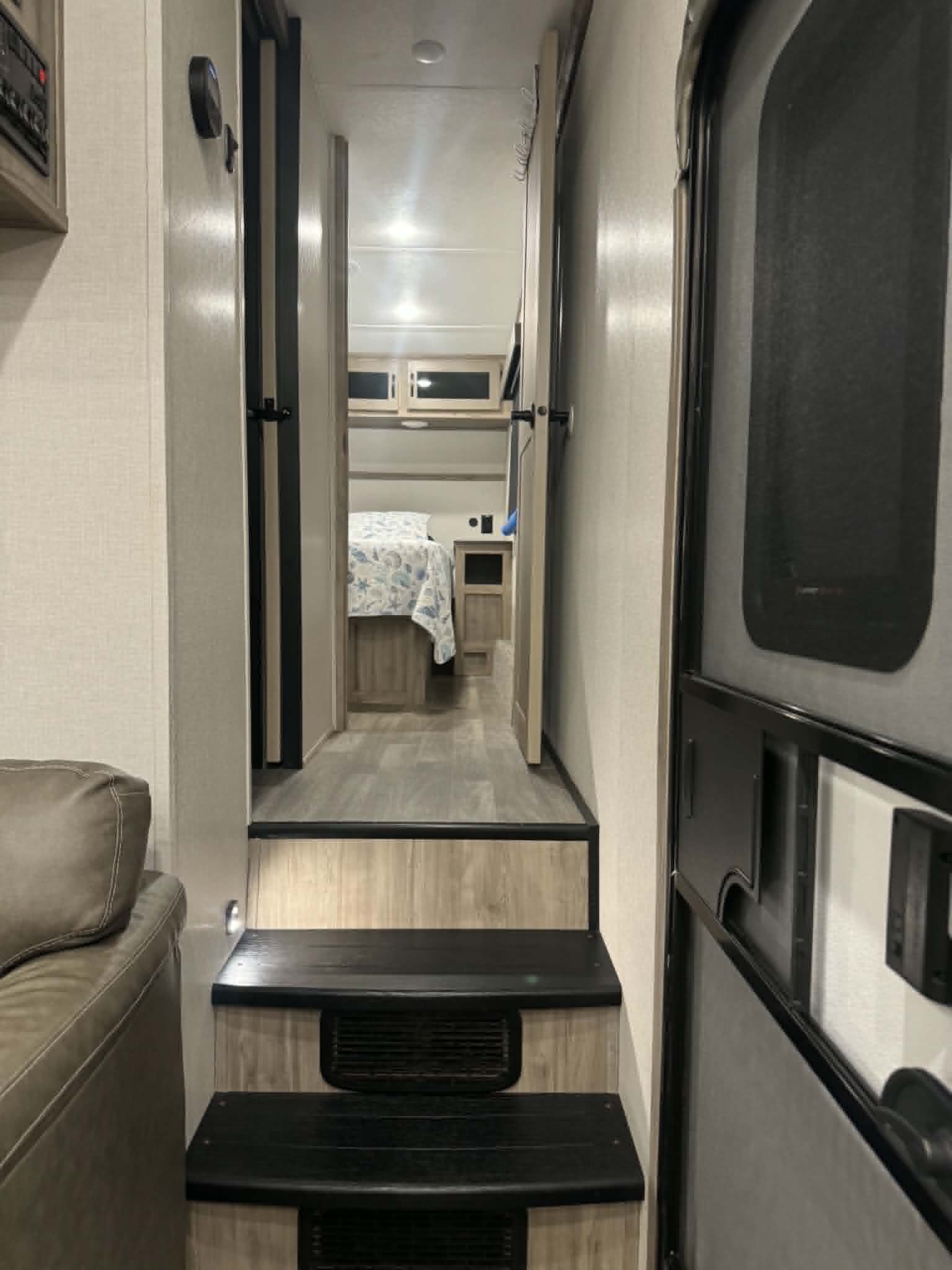 Explore this modern RV rental's inviting interior: comfy living area, functional steps, and a private bedroom beyond the hallway.. Forest River Coachmen Chaparral 2023