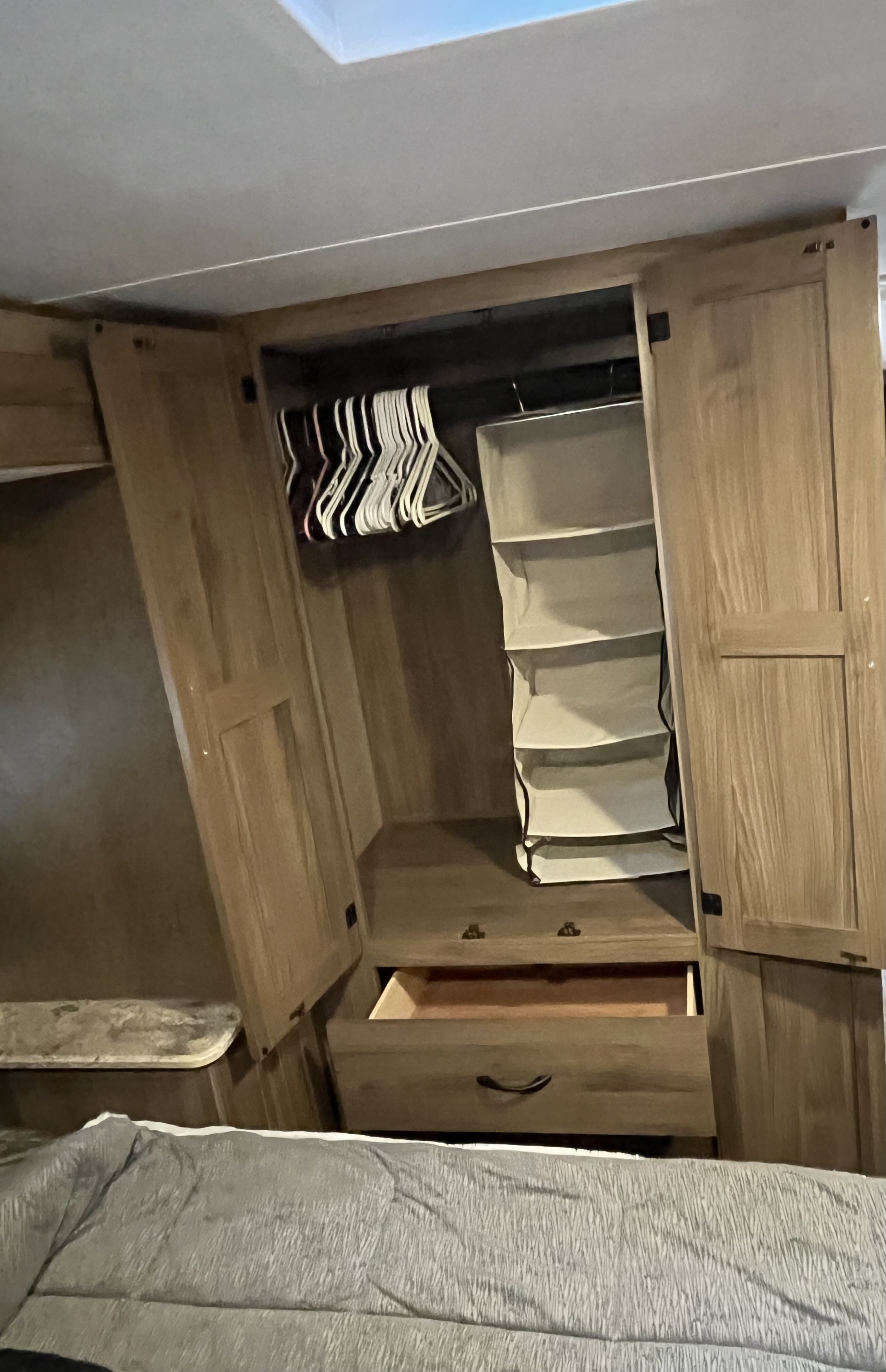 RV rental bedroom interior featuring a wooden closet with hanging clothes storage, a fabric organizer, and a partially open drawer.. Forest River Coachmen Freelander 2017