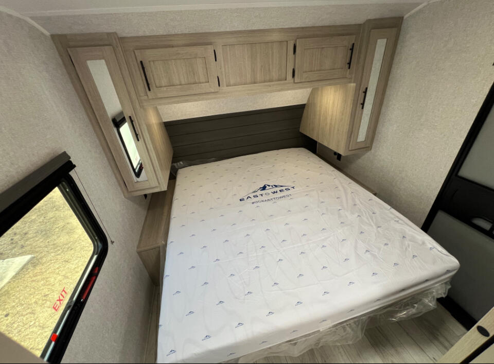 RV rental: Bright bedroom with new East to West mattress, overhead cabinets, and exit window. Ready for your next travel trailer trip.. East to West Della Terra 2026