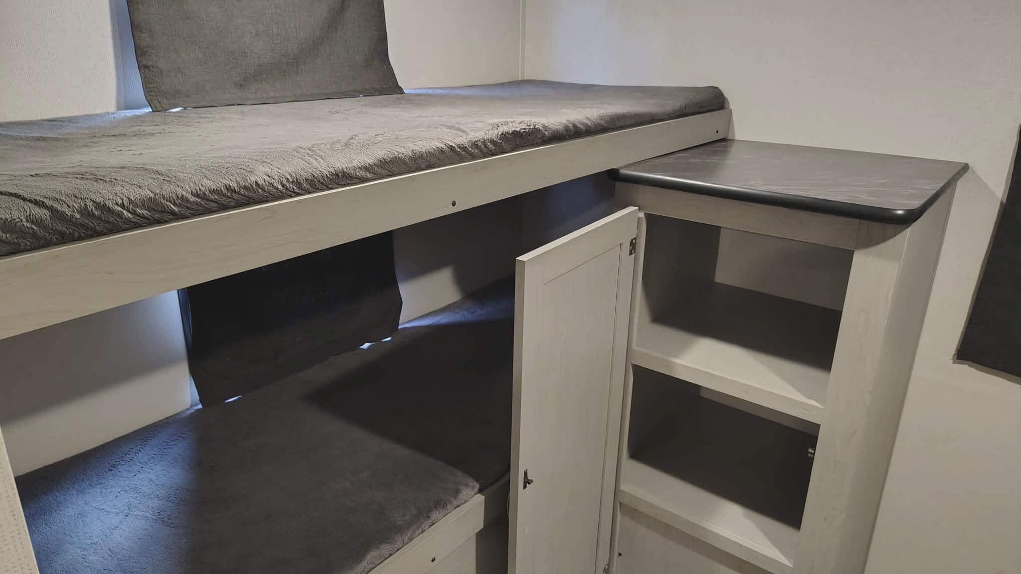 RV rental bunk beds with plush gray bedding & integrated storage unit. Light wood interior, ideal for campers.. Forest River Tracer 2022