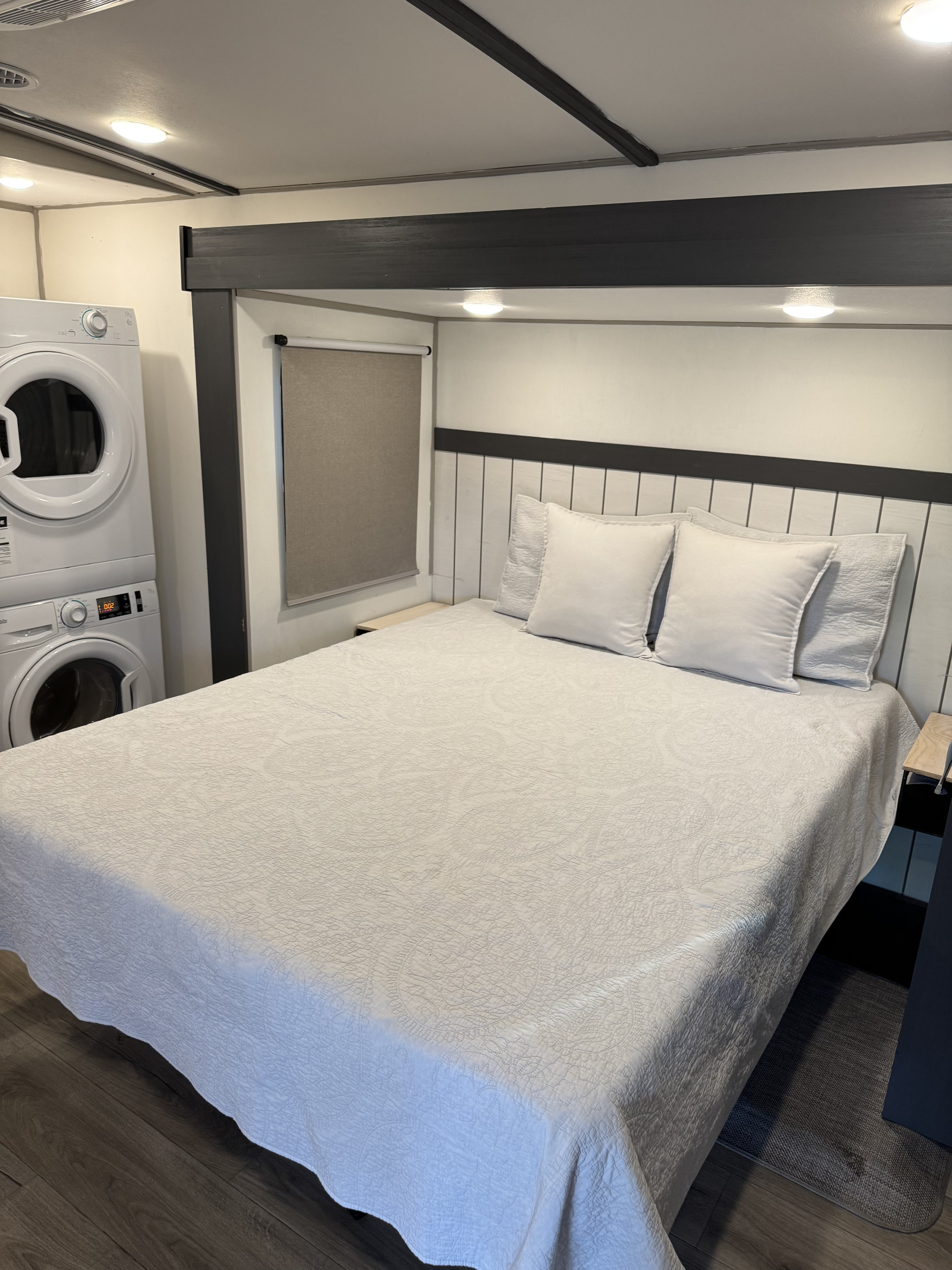 RV rental bedroom featuring a comfortable bed with a modern headboard and a handy stacked washer/dryer unit.. Forest River Salem Hemisphere 2023