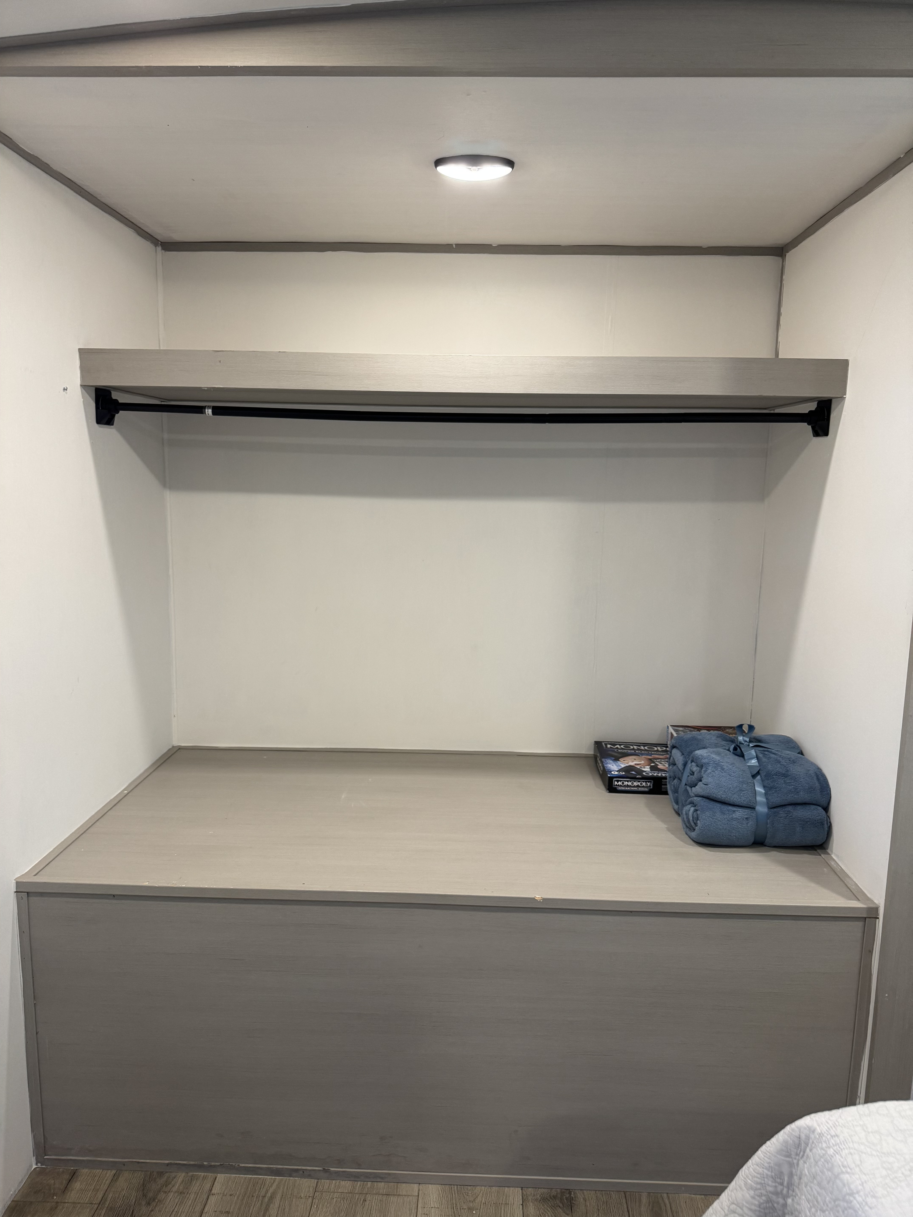 RV rental closet: Brightly lit with a shelf, hanging rod, and lower storage. Blankets & a game sit on the platform.. Forest River Salem Hemisphere 2023