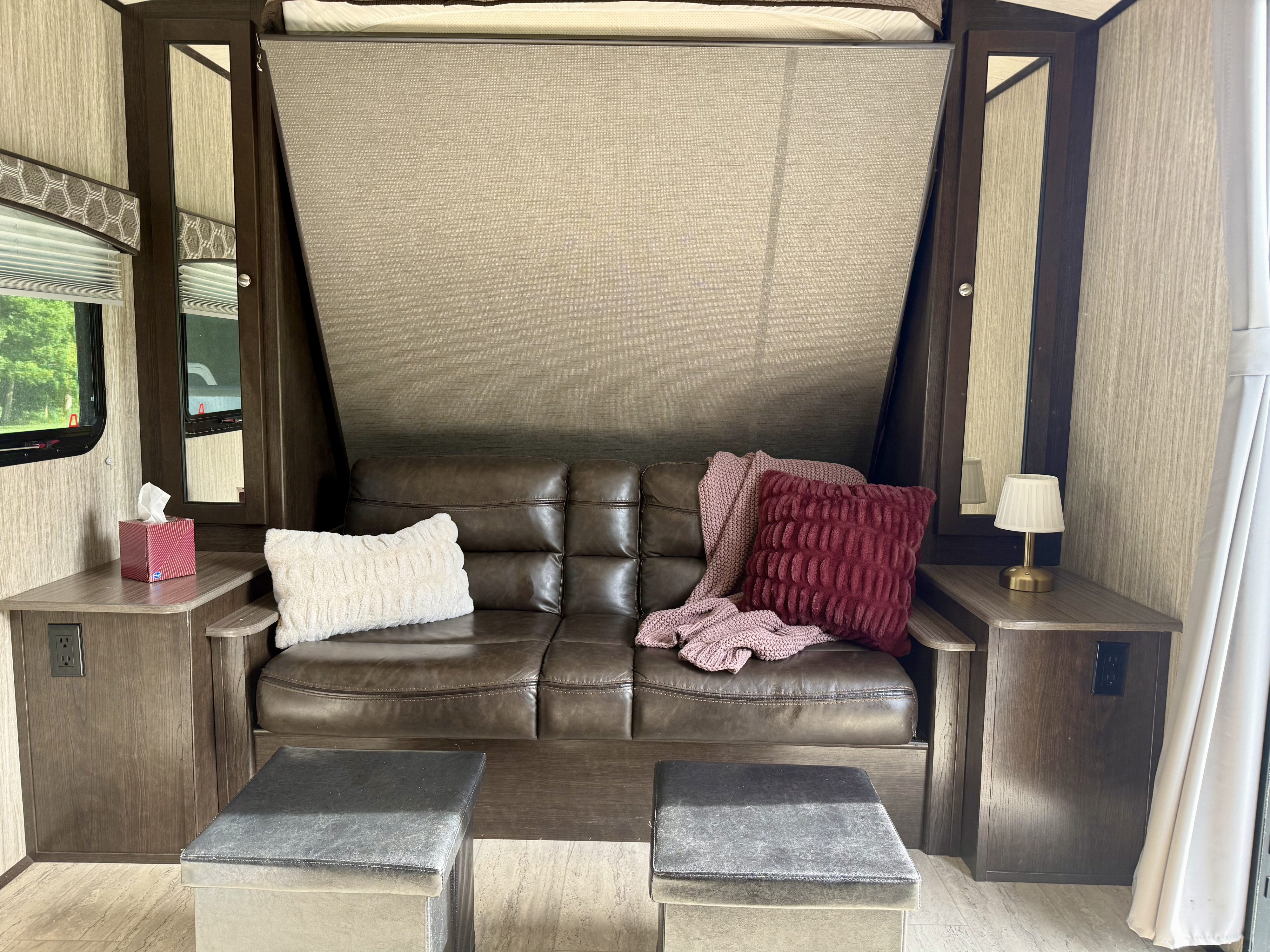Cozy RV rental interior featuring a folded Murphy bed above a leather sofa, side tables, and ottomans.. Cruiser RV Shadow Cruiser 2018