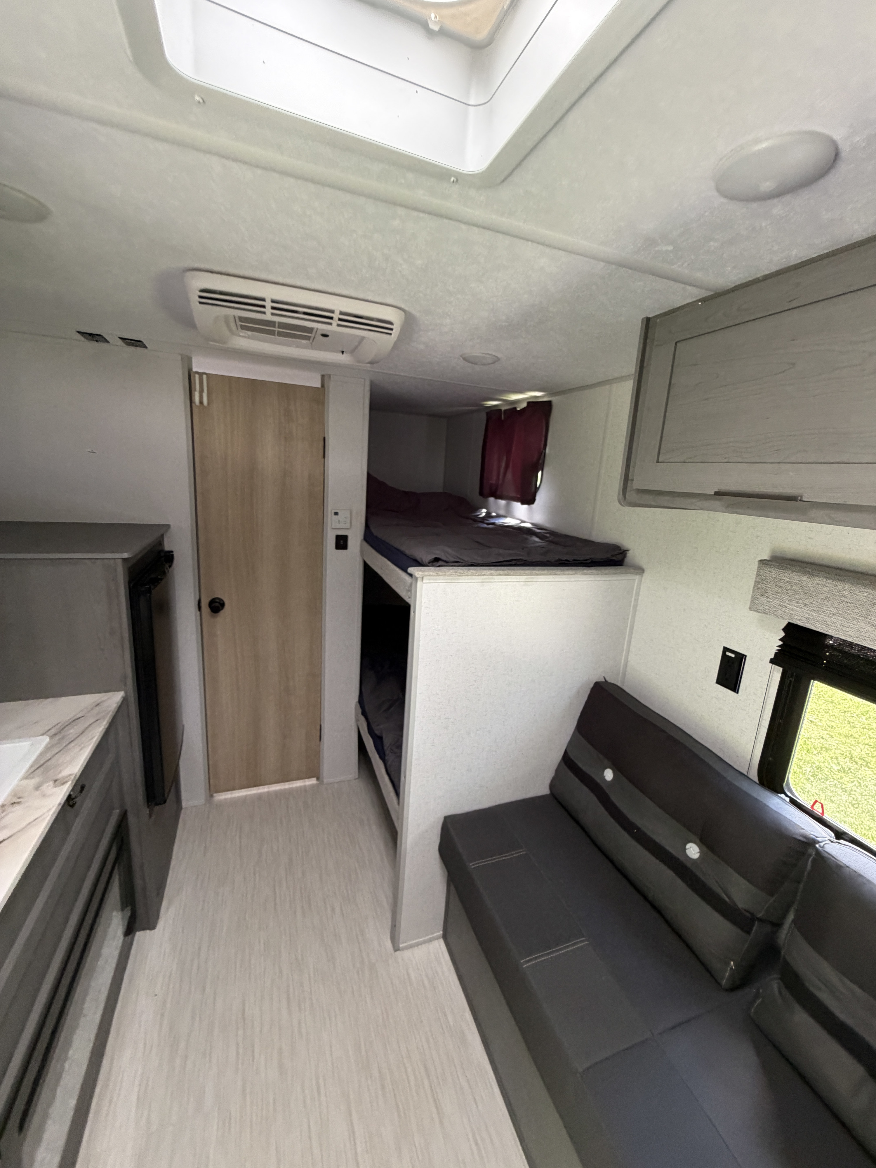 Bright RV rental interior: bunk beds, a sofa, kitchen area, and light floor. Great camper for your next adventure.. Ozark Ozark Trailer 2025