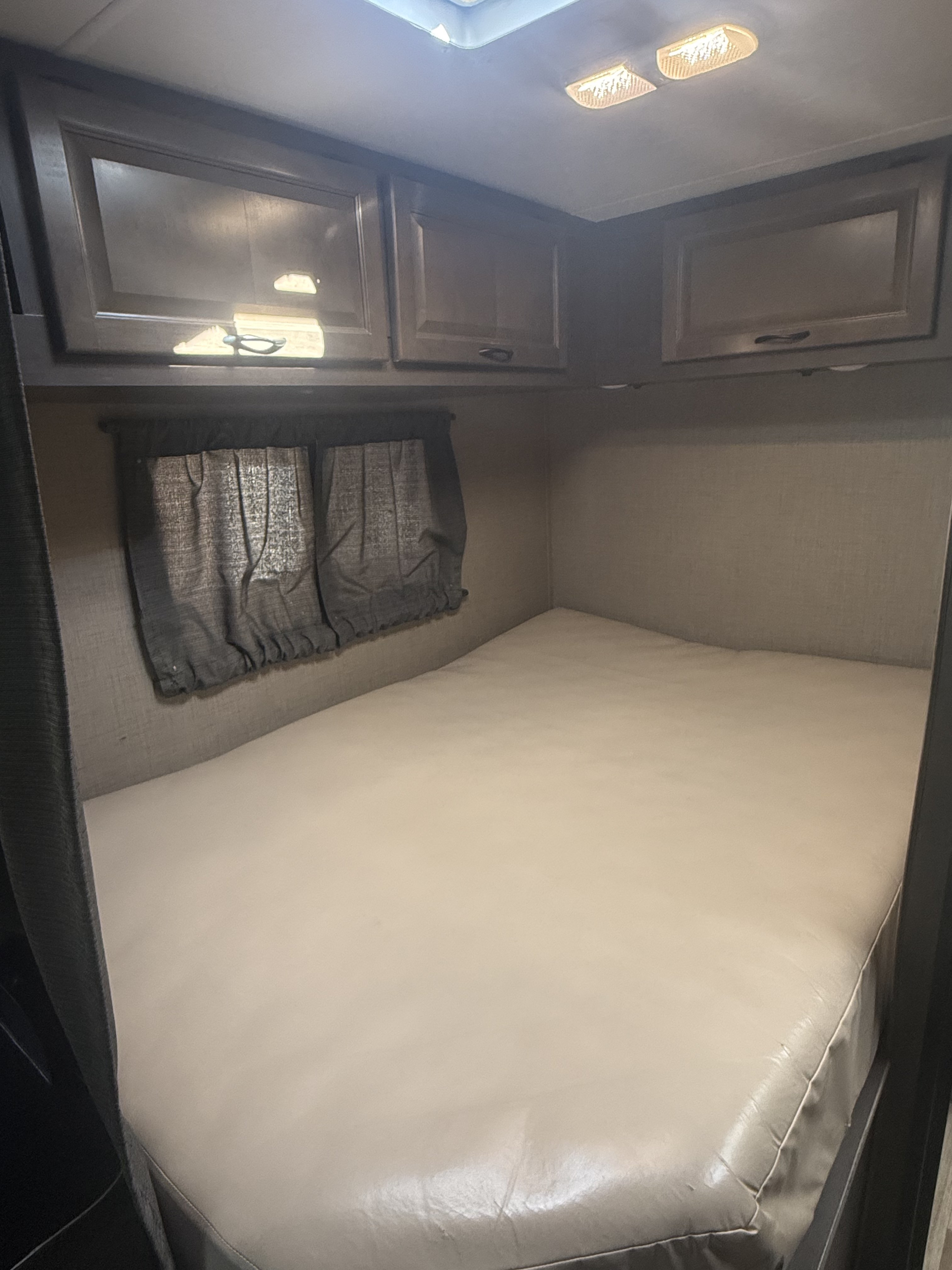 This RV rental bedroom offers a comfortable bed, overhead storage cabinets, and window treatments for privacy.. Thor Majestic 2019
