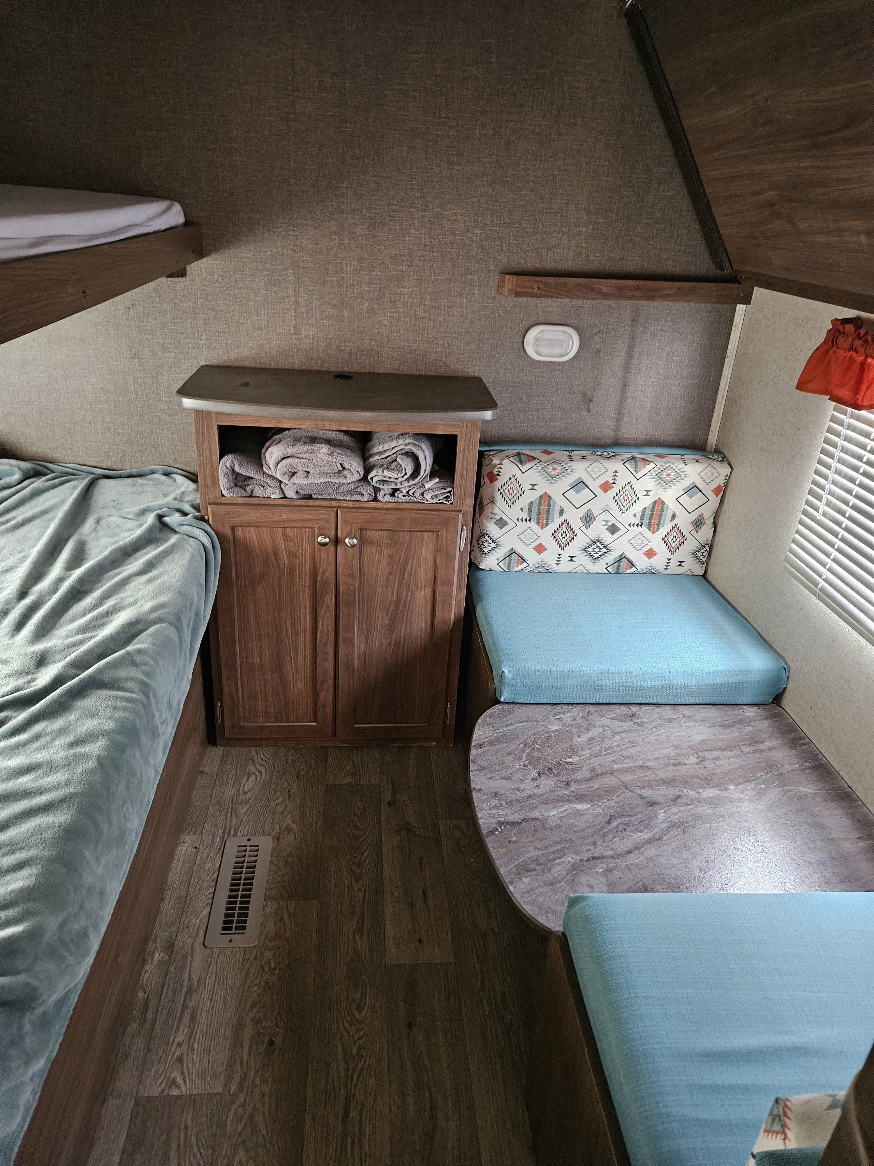 RV rental interior: bunk bed, storage cabinet, blue dinette seating with patterned pillow & table.. Heartland RVs Prowler 2018