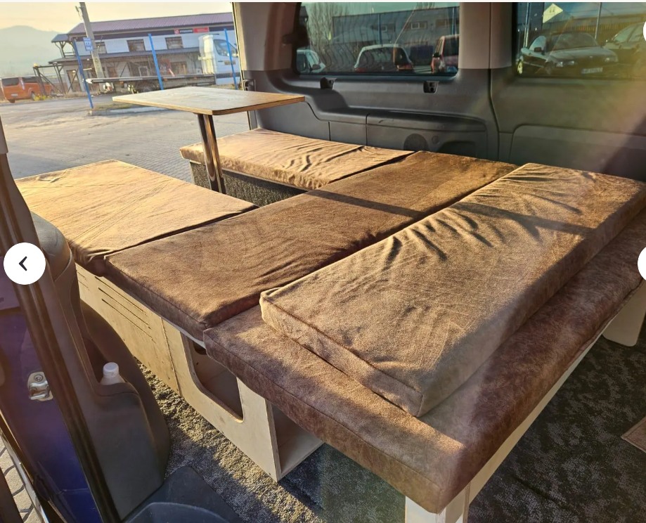 Explore this RV rental's custom camper van interior. Cozy brown cushions form a convertible bed and table setup.. Dodge B Van 2015