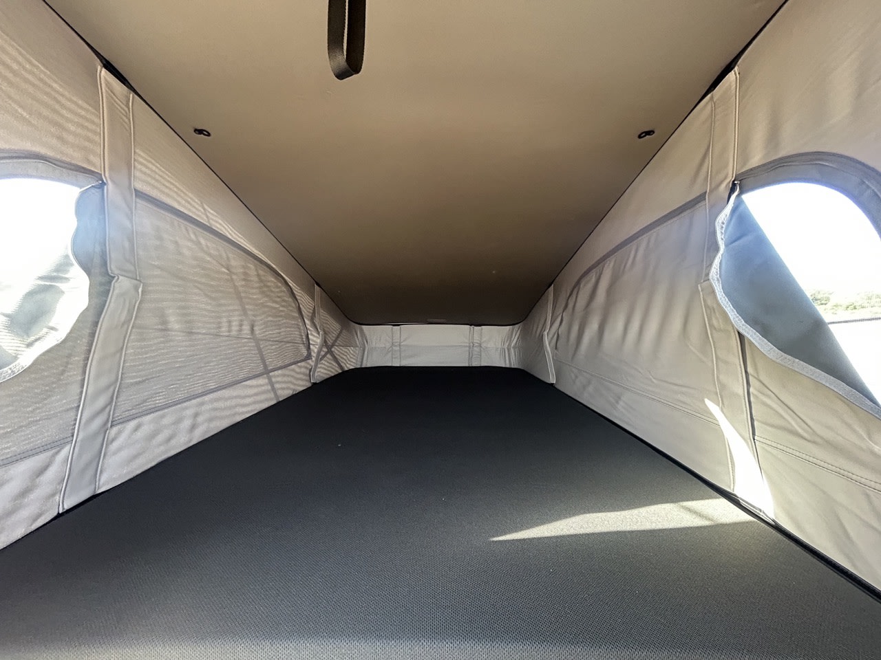 Pop-top RV rental sleeping area with mattress & mesh windows open, offering fresh air and views.. Volkswagen California Ocean 2026