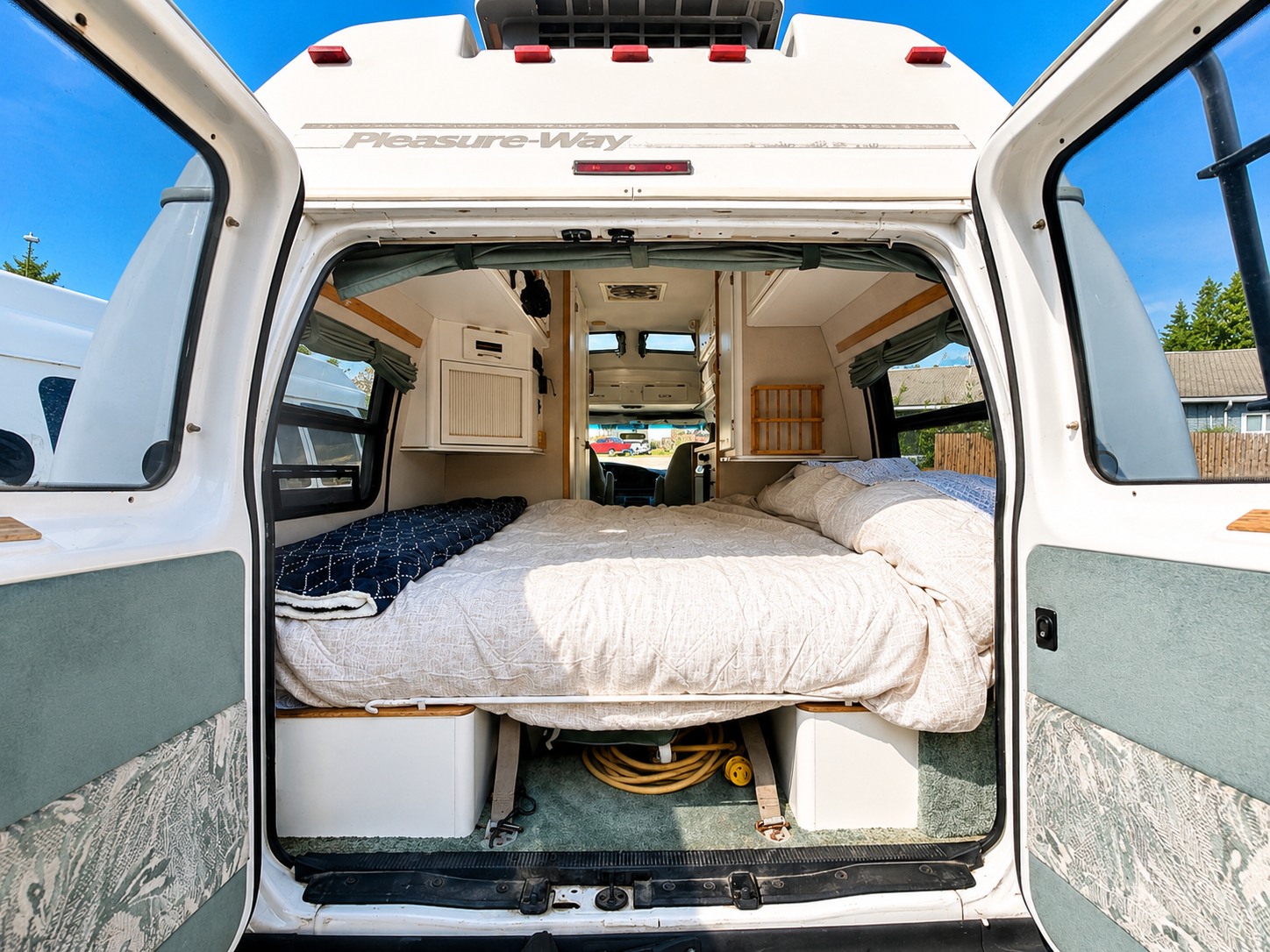 Explore this Pleasure-Way RV rental's cozy interior, featuring a comfortable bed for your next camper van adventure.. Pleasure-Way Excel TS 2002