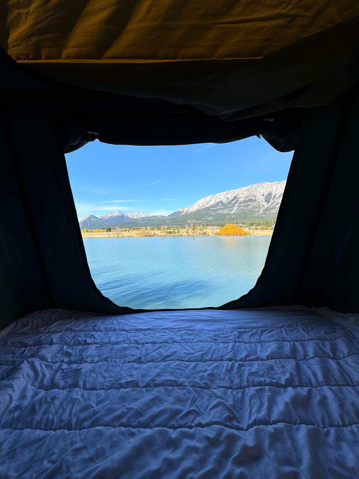 Cozy RV rental tent view: serene lake, snowy mountains, autumn trees. Relax on the comfy bed inside.. Toyota RAV4 Trail AWD 2021