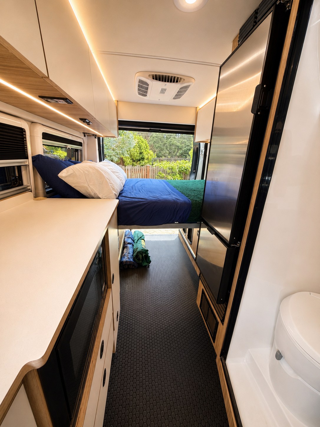 RV rental: Modern camper van interior with a cozy bed, sleek kitchen counter, large fridge, and compact bathroom with a toilet.. Coachmen Pixel 2025