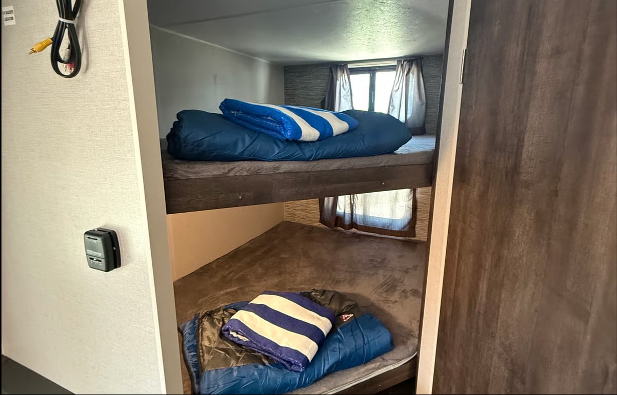 Cozy RV rental bunk beds with sleeping bags and blankets, ideal for family travel. RV interior shown.. KZ SPORTSMAN SE 2020