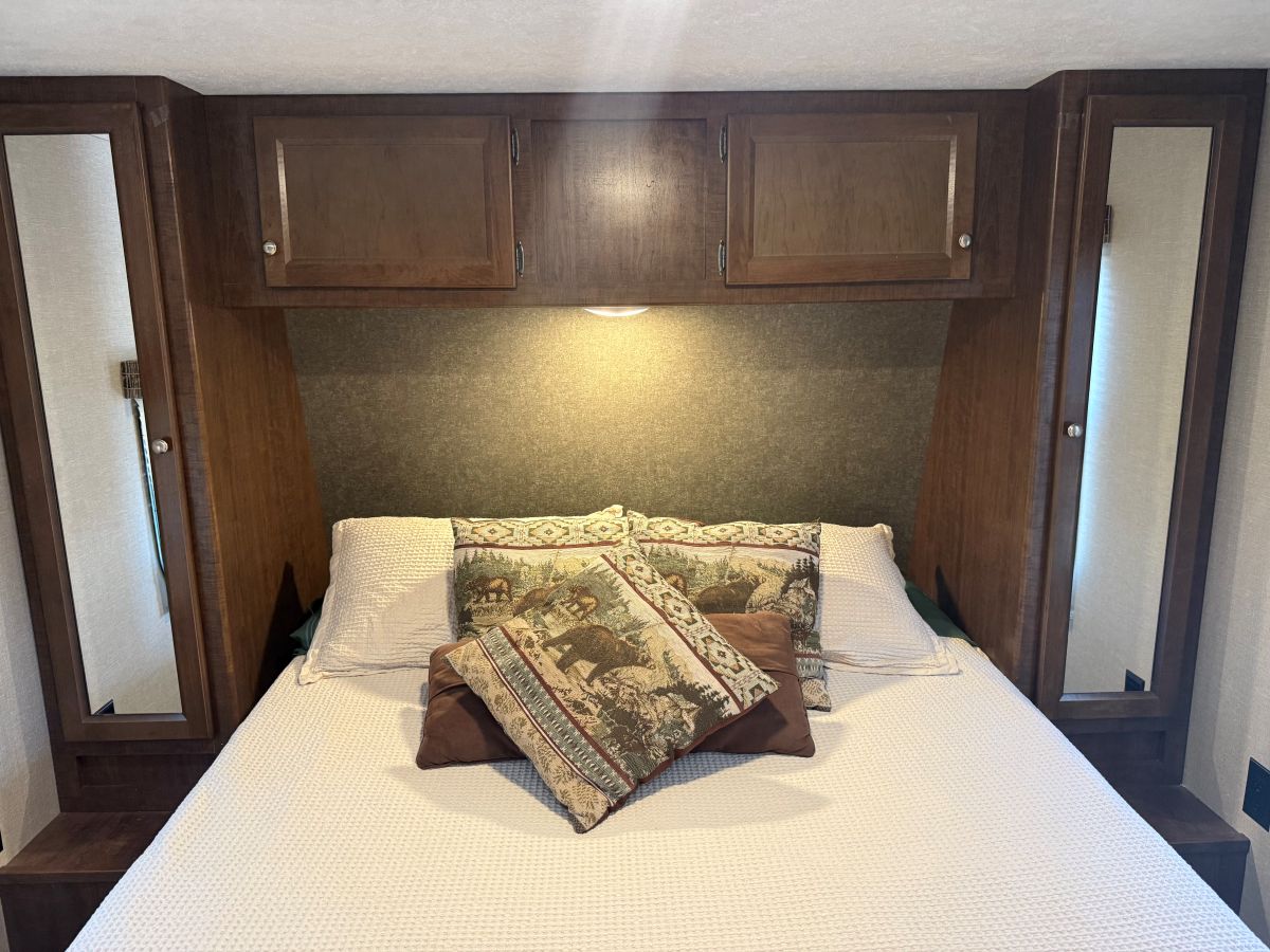 RV rental bedroom: cozy bed with nature pillows, overhead cabinets, and mirrored wardrobes for compact storage.. Keystone RV Hideout 2018