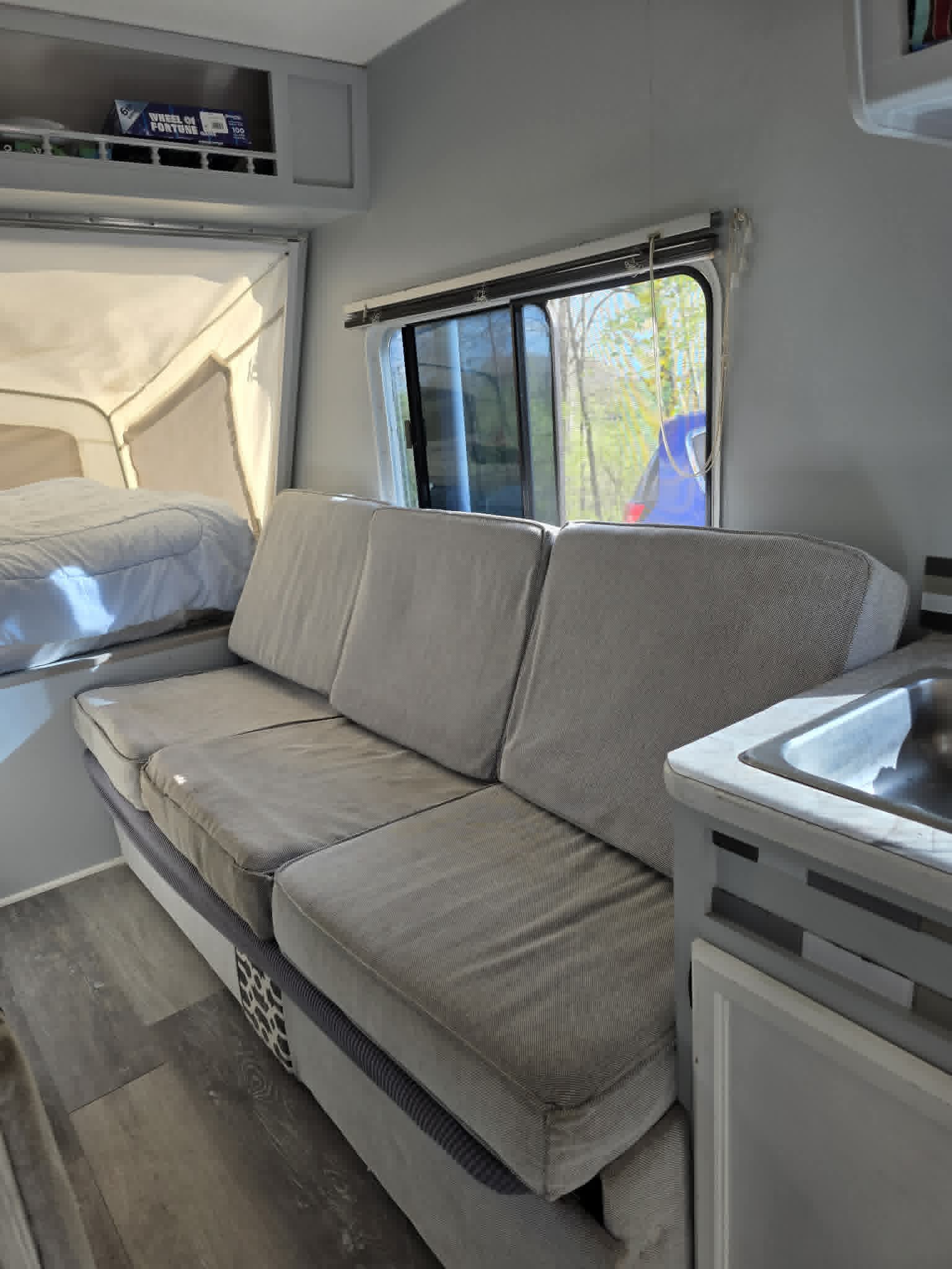 Inside a comfy RV rental: view of the sofa, pop-out bed, & kitchen counter with sink. Ready for your next trip.. R-Vision Trail-Lite Bantam 2003