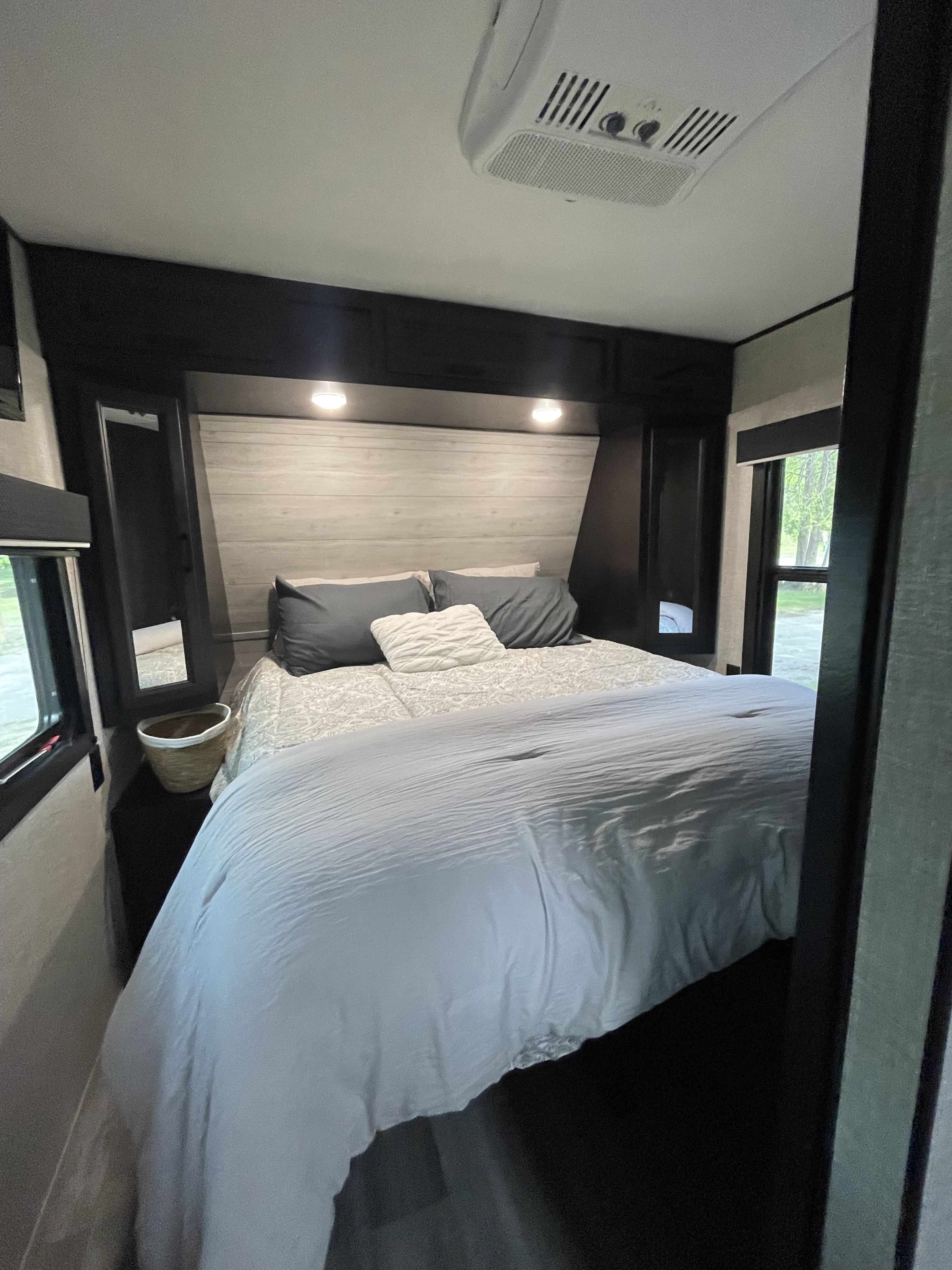 Comfortable RV rental bedroom with a well-made bed, modern headboard, overhead lighting, and AC unit for a great stay.. Jayco Jay Flight 2022