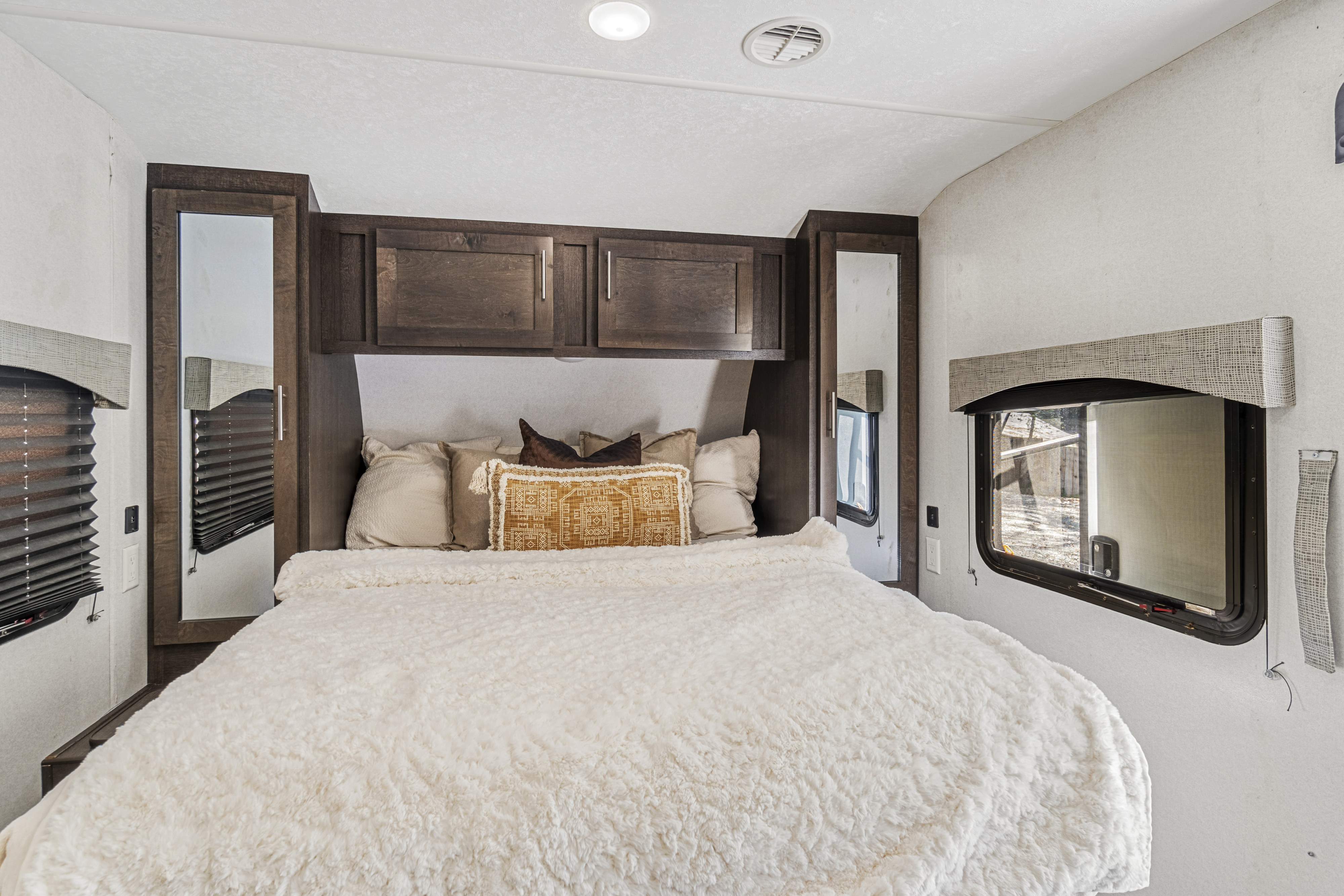 Experience comfort in this RV rental bedroom featuring a plush bed, ample overhead storage, and natural light from the windows.. Forest River Evo T2550 2019