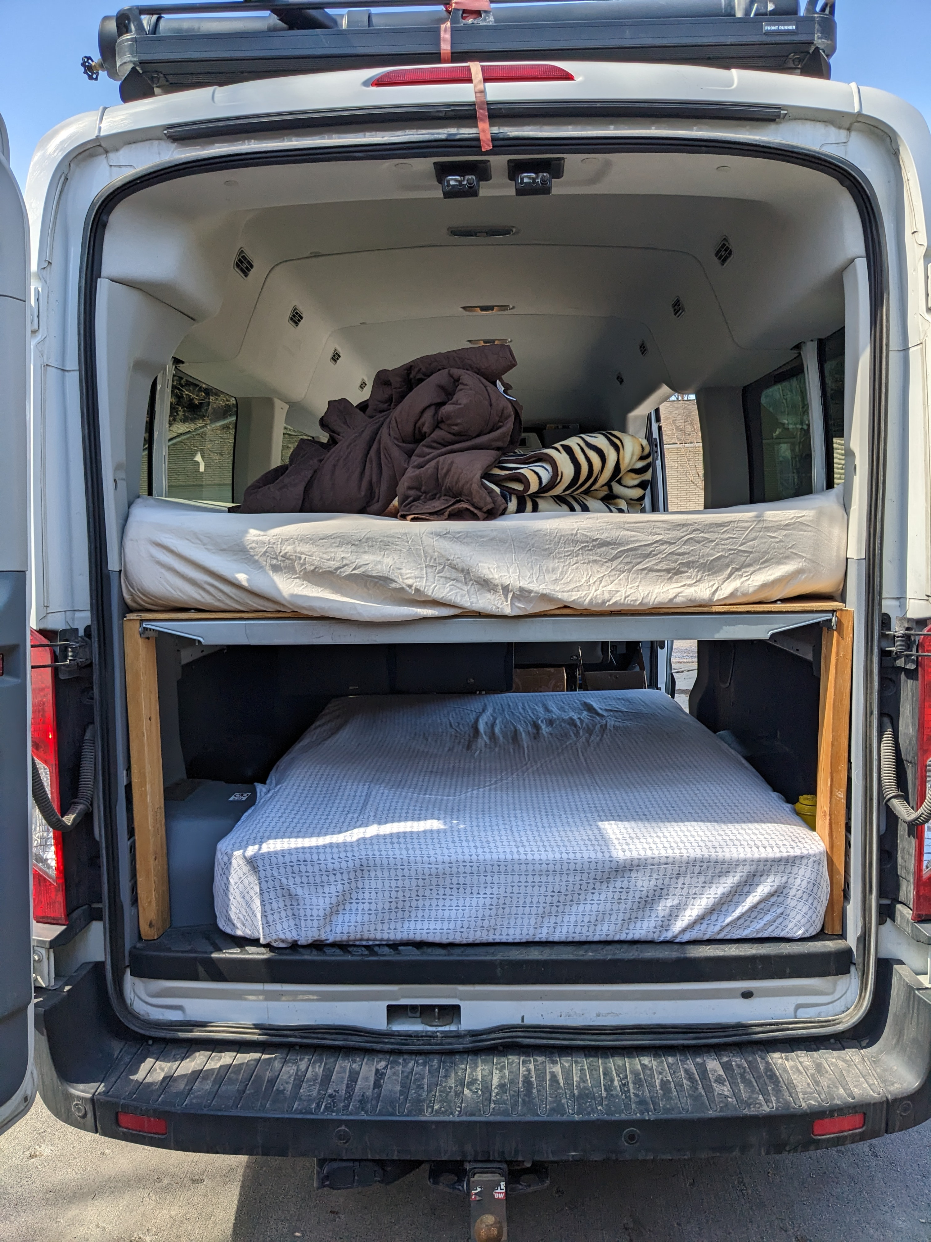 White rv rental camper van interior featuring a two-tier bunk bed setup with mattresses and bedding for travel.. Ford Transit 2016