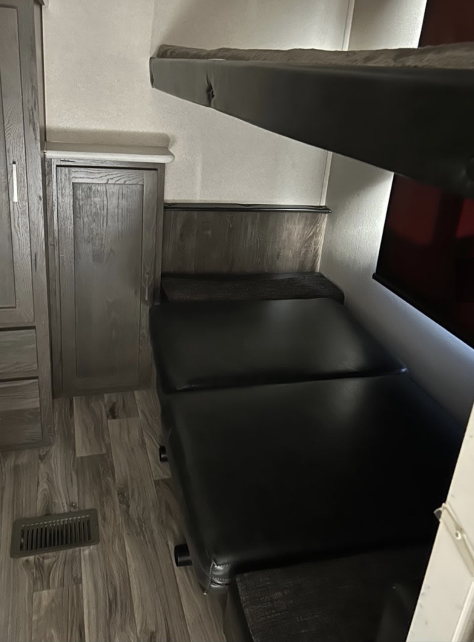 RV rental interior showing an upper bunk bed over a lower convertible bed/seating, storage, and wood-look floor.. Forest River Salem Hemisphere Lite 2019