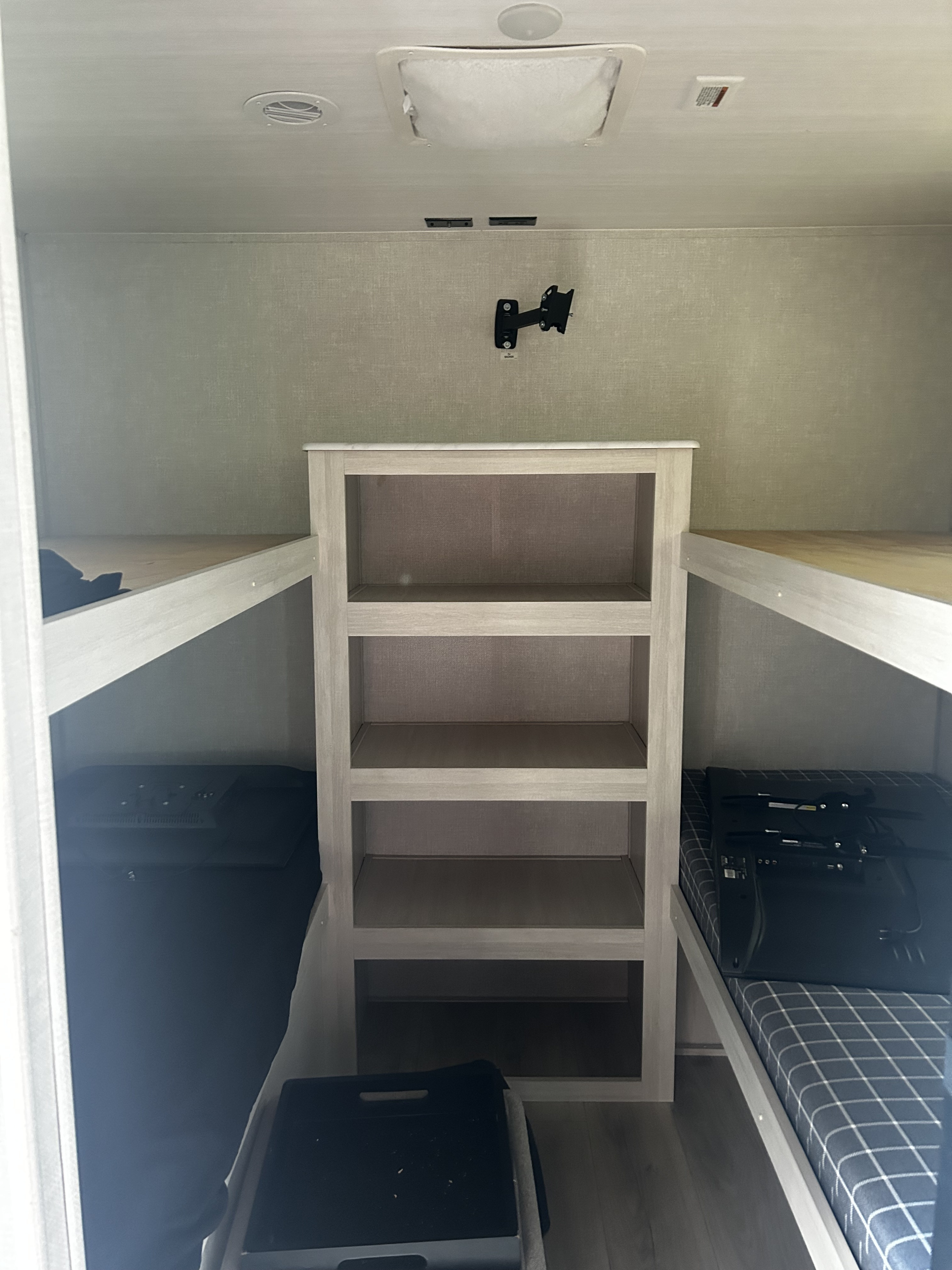 This RV rental's bunk area features stacked beds, a central shelf unit, and a TV mount, optimized for comfortable travel.. Forest River Surveyor Legend X 2025