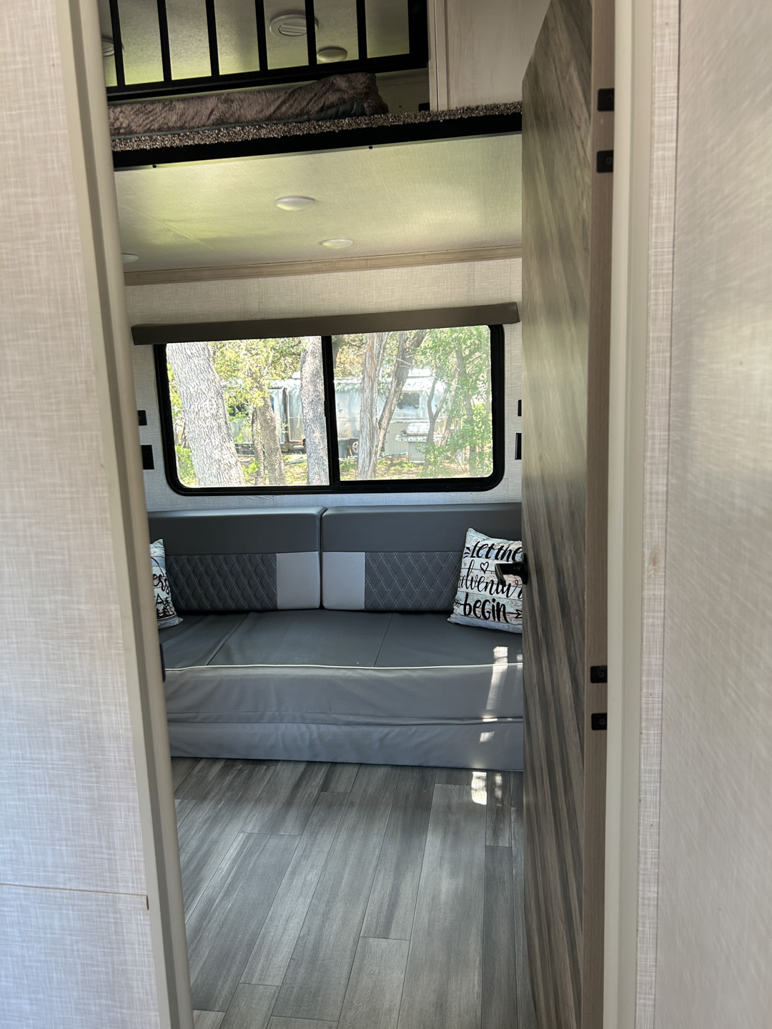 Step inside this modern rv rental: grey seating, scenic window, and an upper sleeping loft with a bed.. Forest River Impression 2022