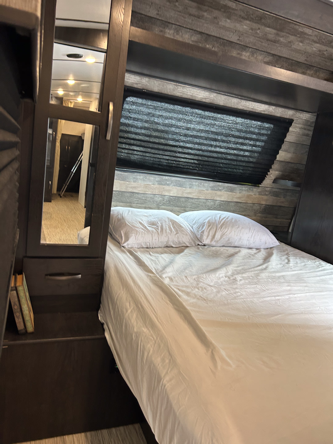 Cozy RV rental bedroom with comfortable bed, window with blinds, and mirrored storage, reflecting a hallway view.. Surveyor Legend 2021