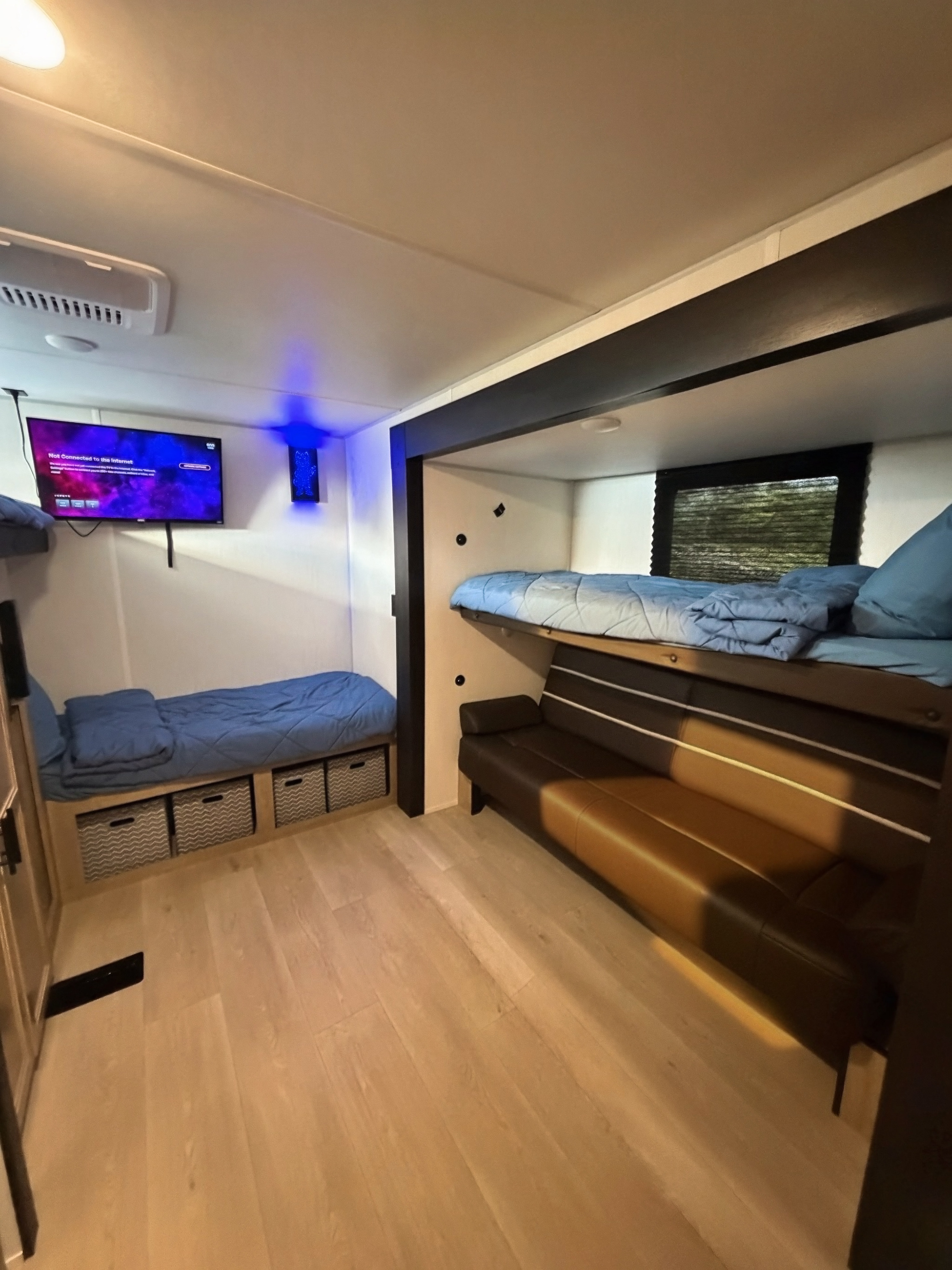 Cozy RV rental interior with bunk beds, a sofa, and TV. Ideal for families, featuring clever storage and light wood floors.. Forest River CHEROKEE WOLF DEN 301BH 2026