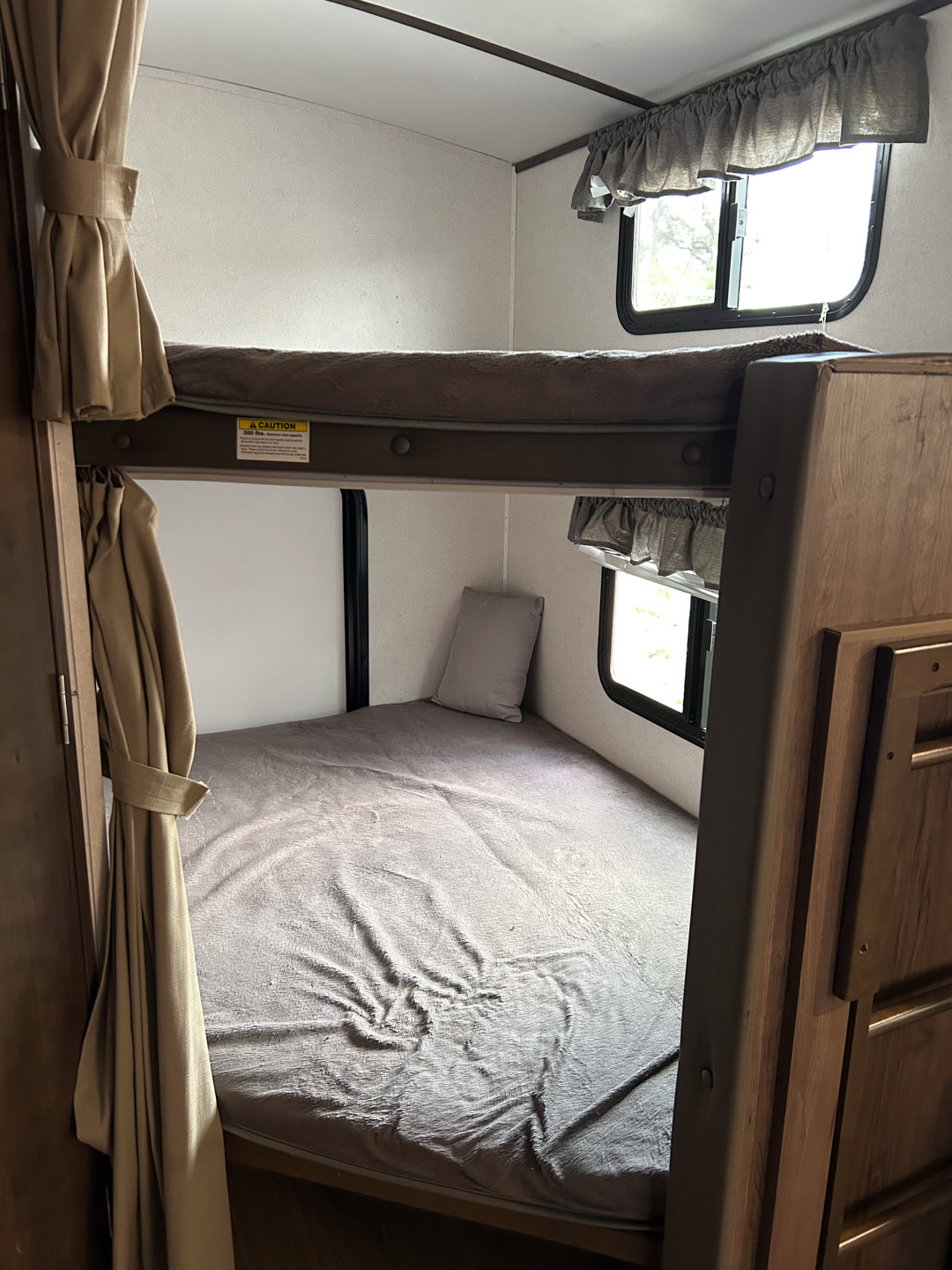 An rv rental bunk area with comfortable upper and lower beds, each fitted with bedding and nearby windows.. Keystone RV Passport 2021