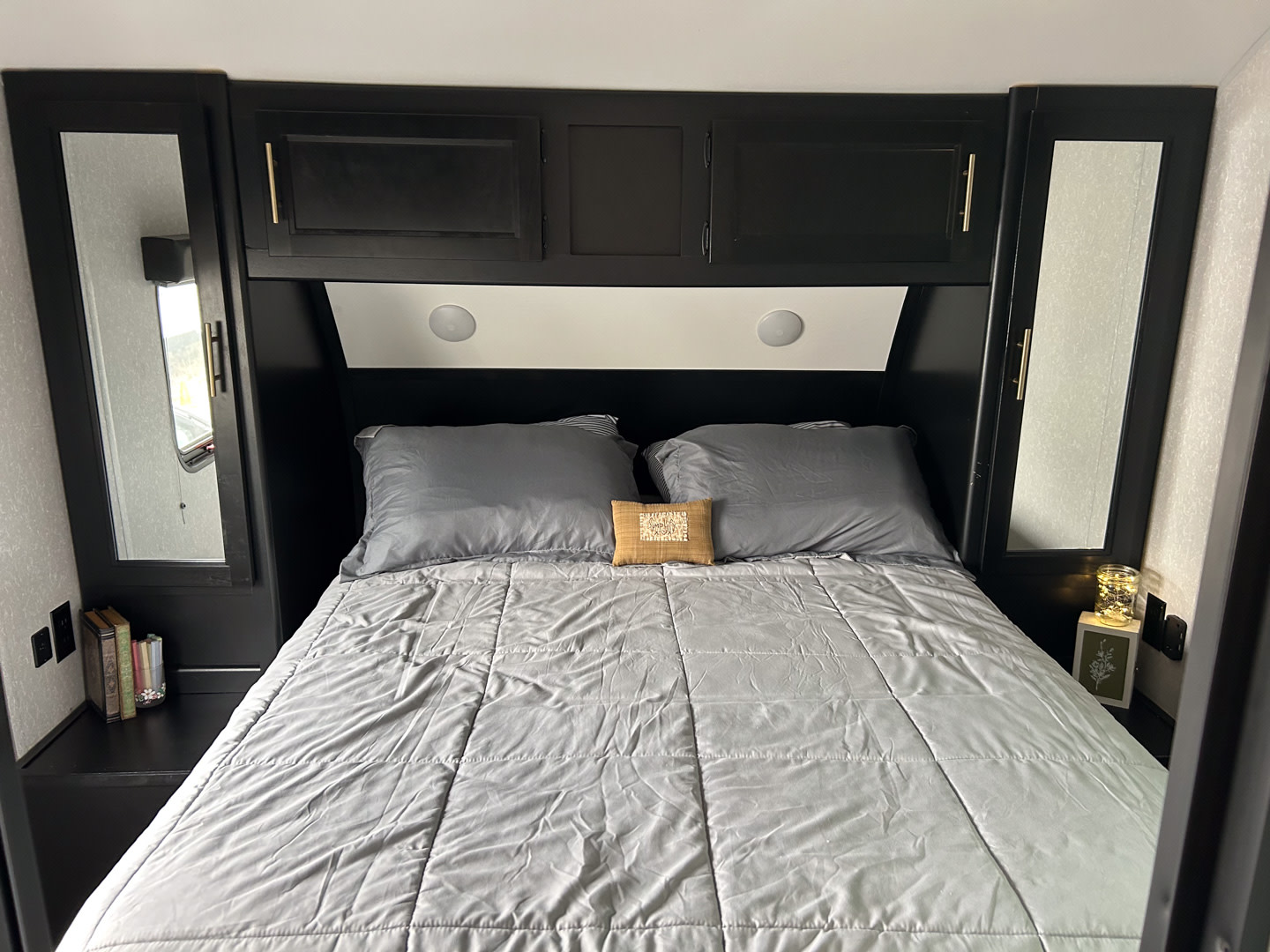 Comfortable RV rental bedroom featuring a grey bed, dark wood built-in cabinets, and mirrored side wardrobes.. Forest River Cherokee Grey Wolf 2022