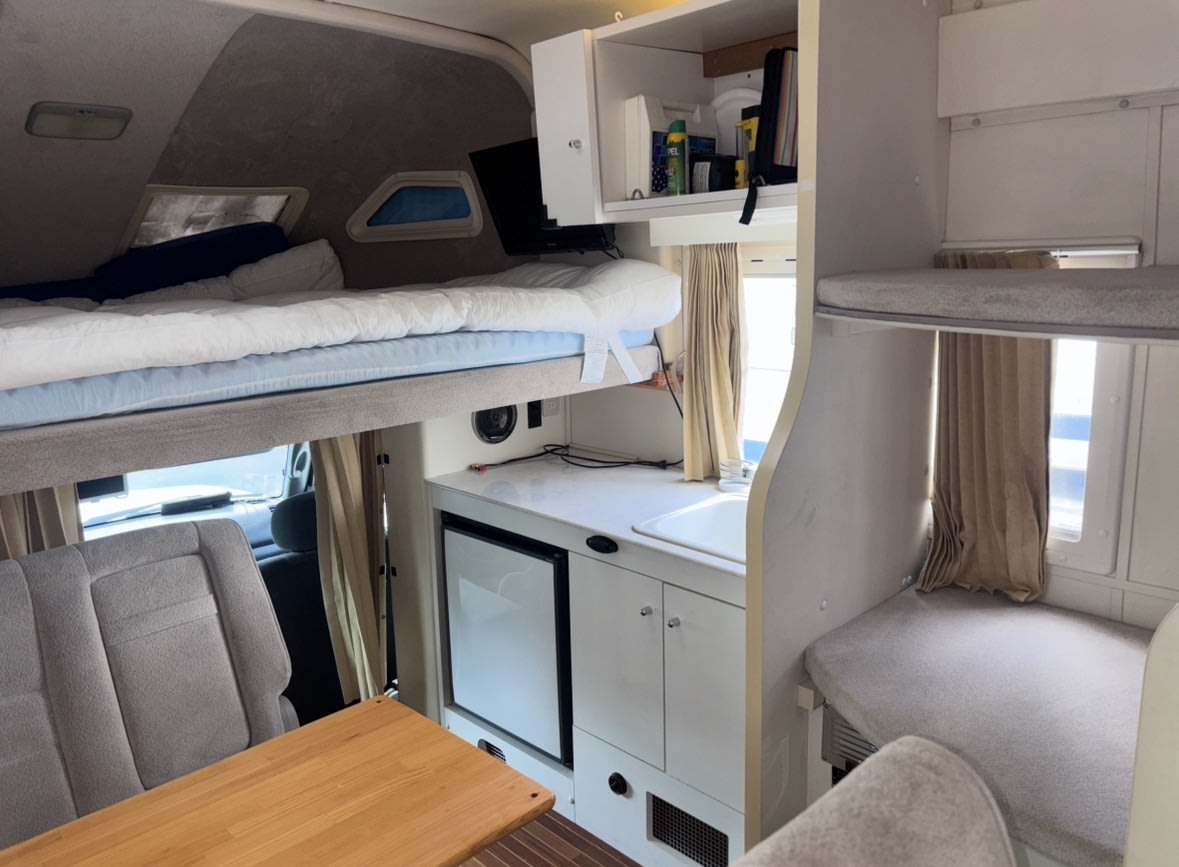 Cozy rv rental interior: overhead and bunk beds, kitchenette with sink & fridge, and dining area. Ready for adventure!. 5TBKT44114S447491 Toyota Tundra Excruiser 2004