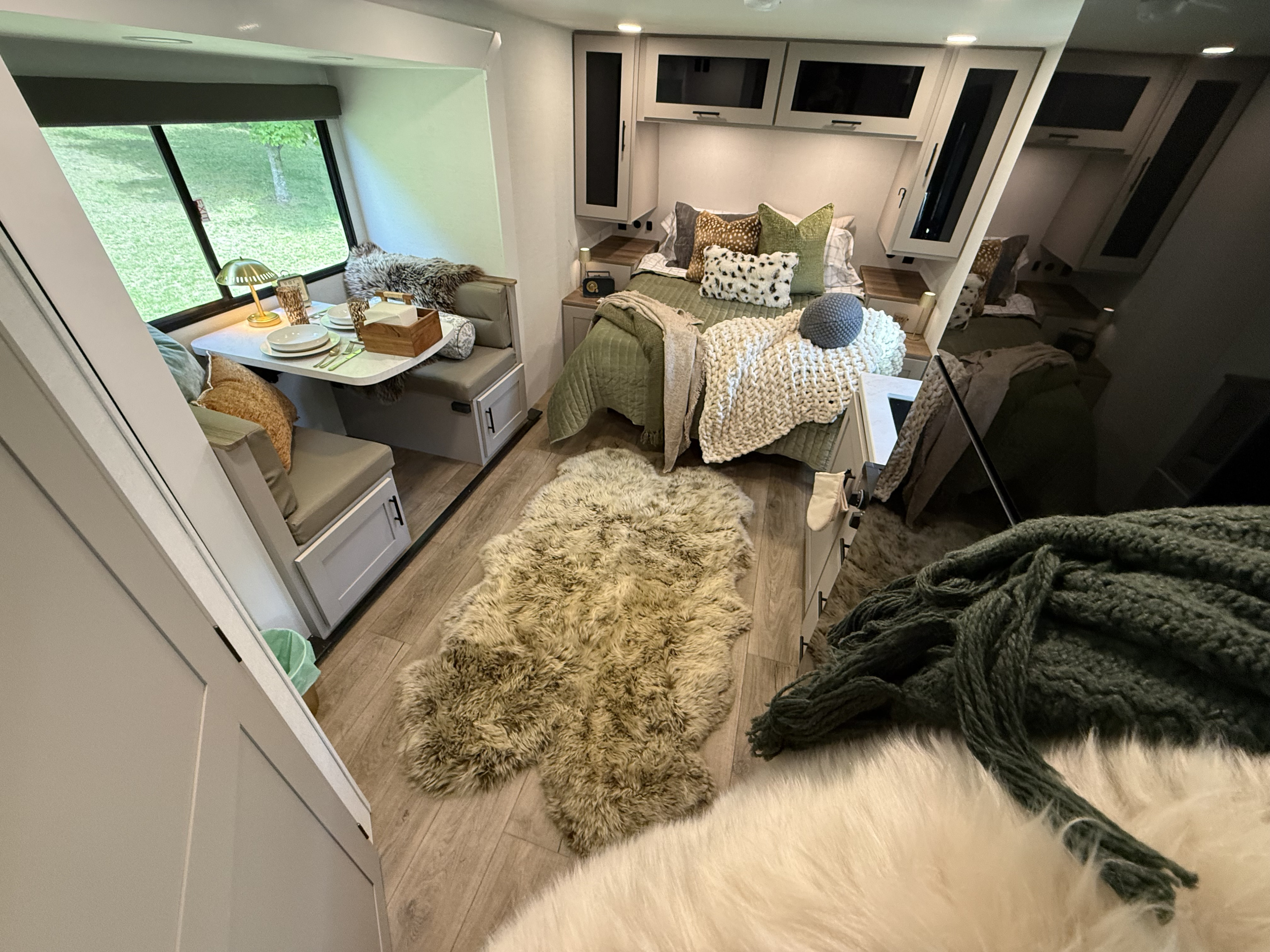 Cozy RV rental interior featuring a dining nook with place settings, a comfortable bed, and a scenic window view.. Alliance Delta Solo BH181 2026