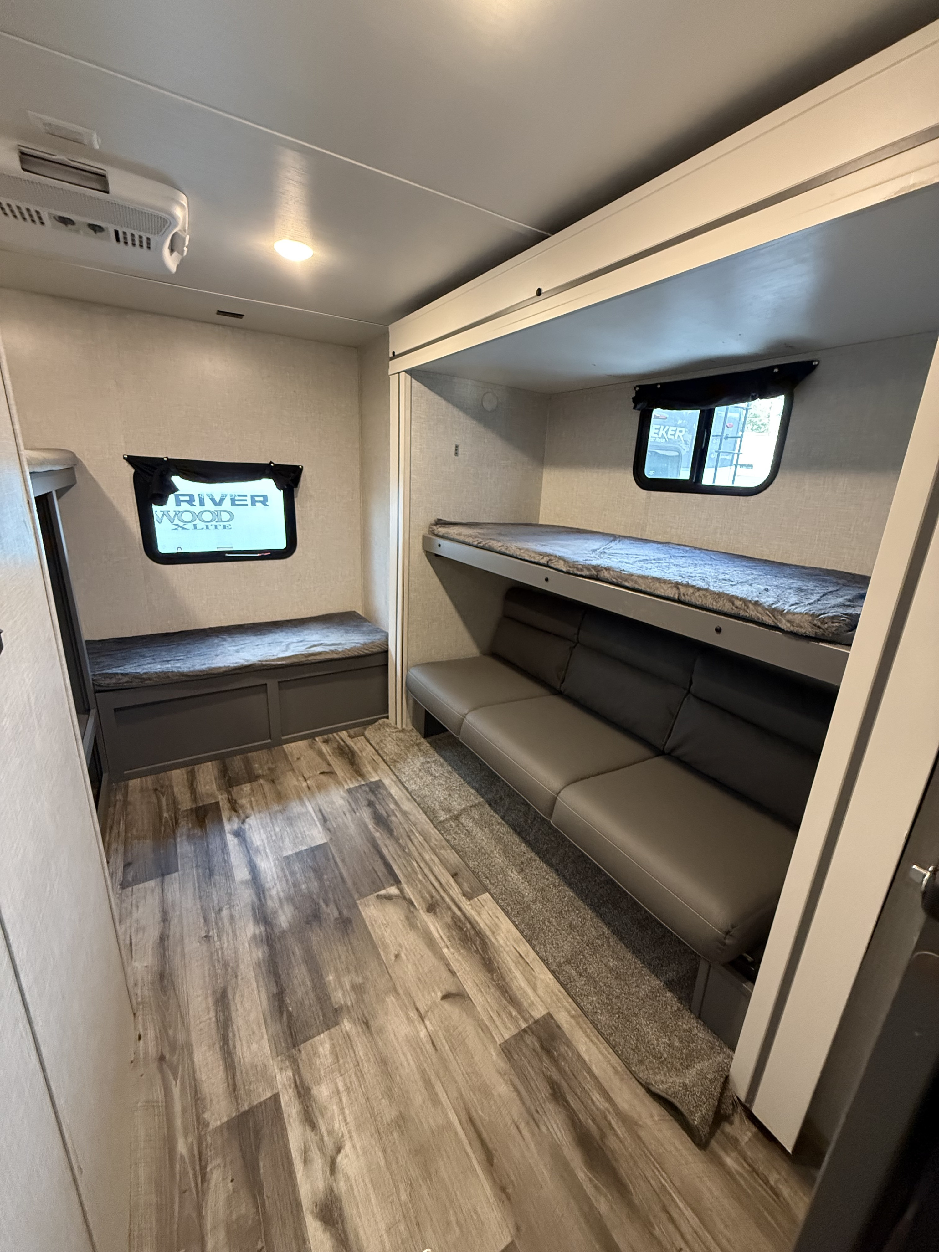 This cozy rv rental bunkhouse features beds, seating, light wood floors, AC, and windows.. Crossroads RV Volante 2023