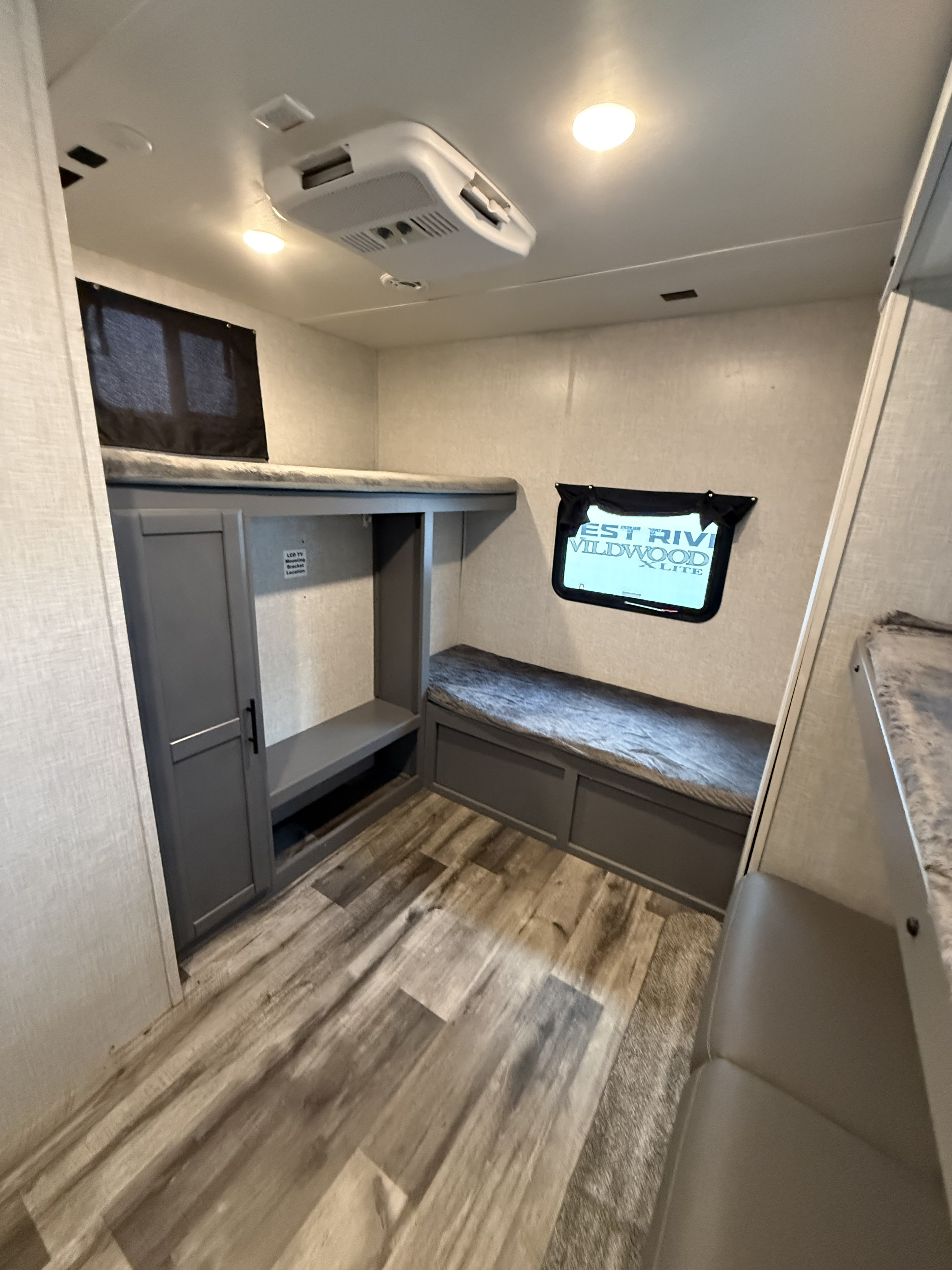 Inside this RV rental, discover bunk beds, a storage cabinet, bench seating, and wood-patterned flooring under bright ceiling lights.. Crossroads RV Volante 2023