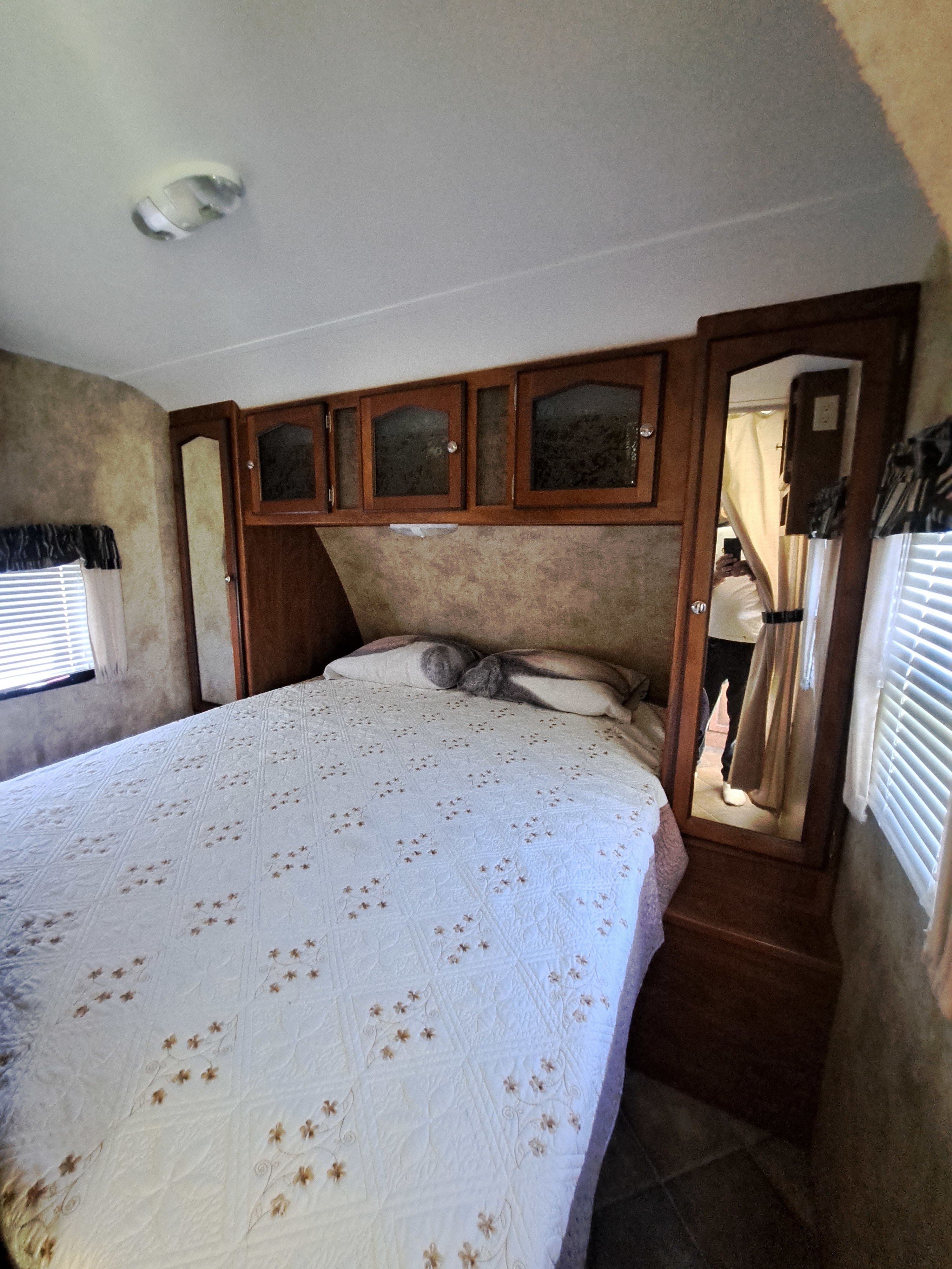 Inviting RV rental bedroom with a comfy bed, wood overhead cabinets, and a full-length mirror. Great for road trips.. Keystone RV Passport Ultra Lite 2012