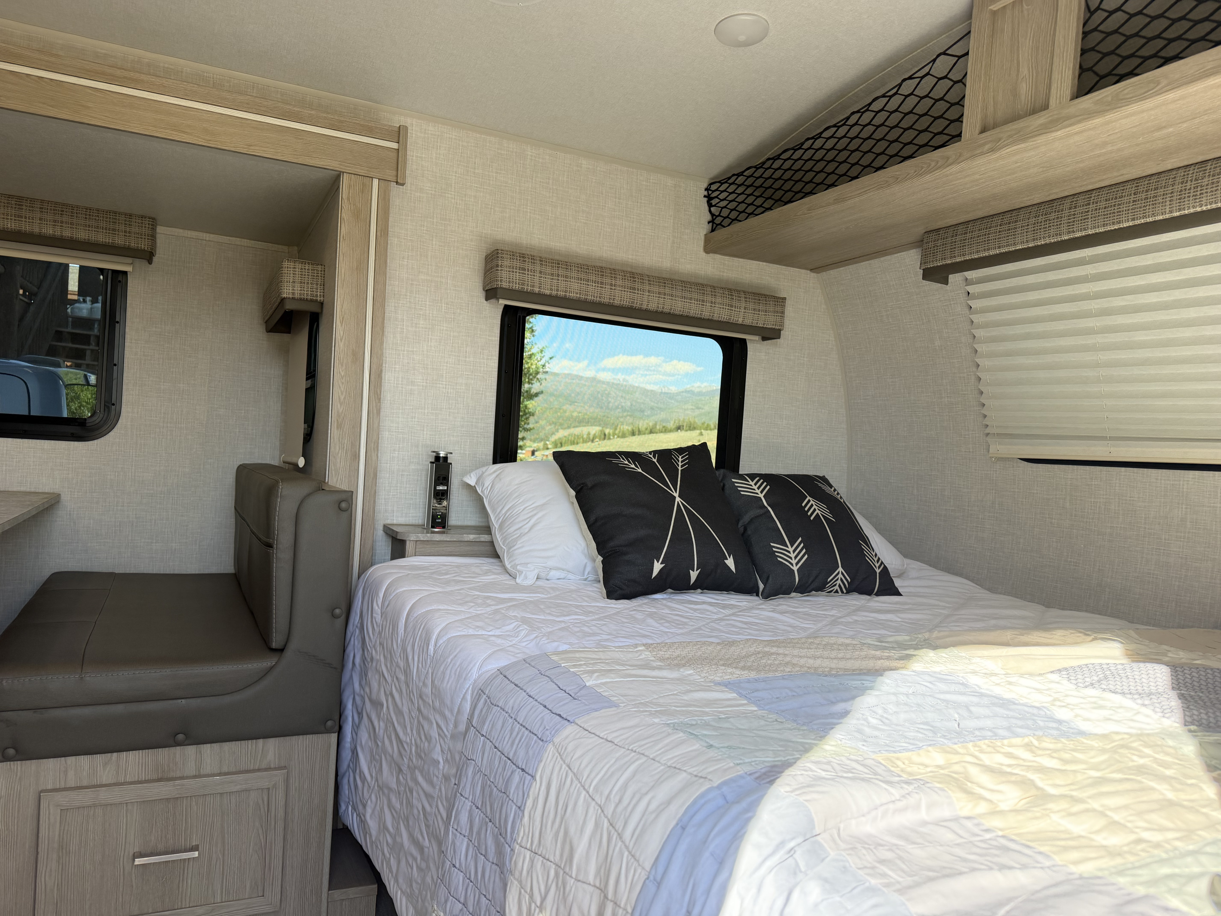 Cozy RV rental bedroom with a comfy bed, scenic mountain view, compact seating, and overhead storage for your travels.. Forest River Flagstaff E-Pro 2022