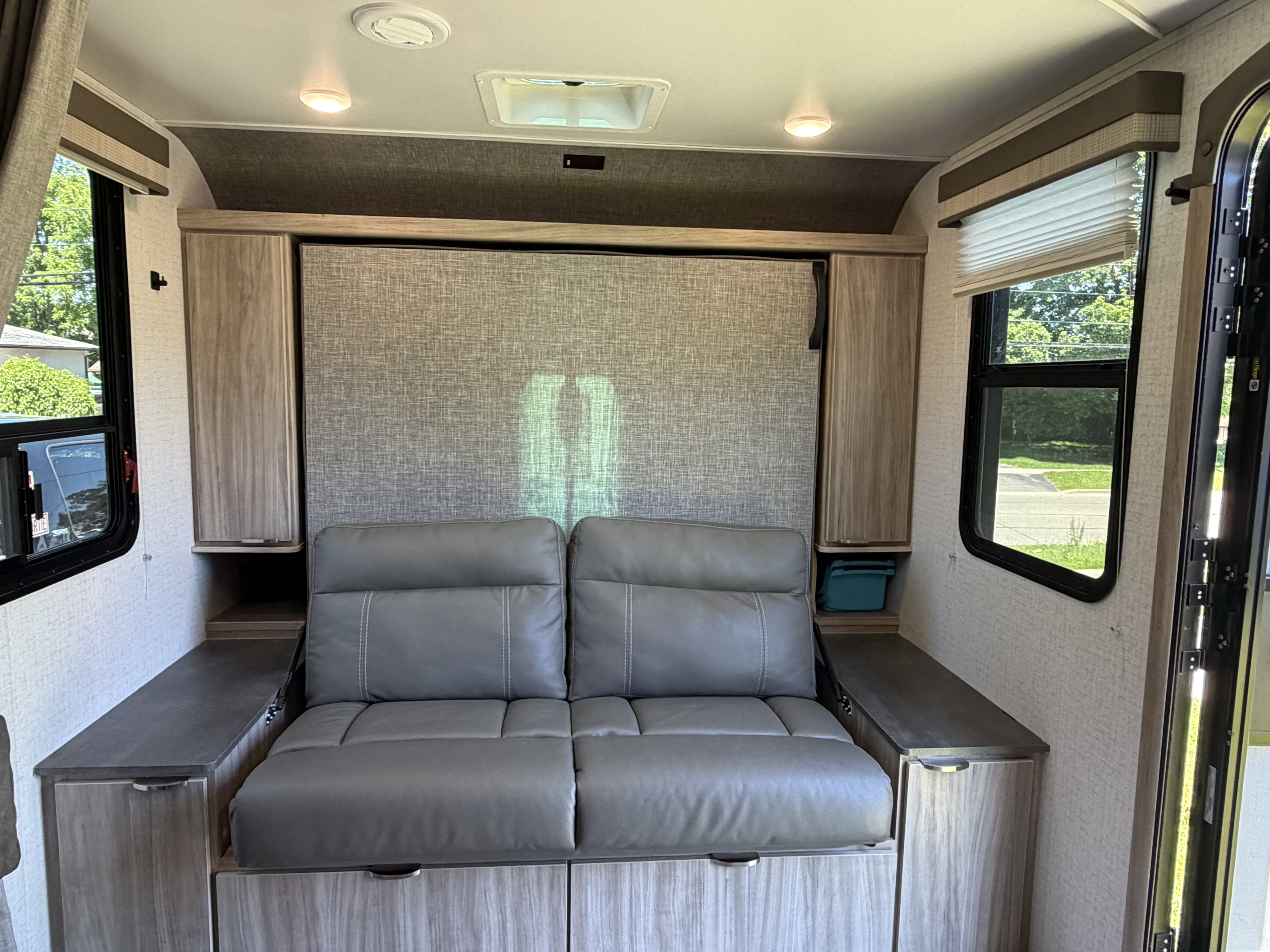 Inside this RV rental: a versatile sofa that converts to a bed, surrounded by practical storage and bright windows.. Minnie Micro Minnie 2021