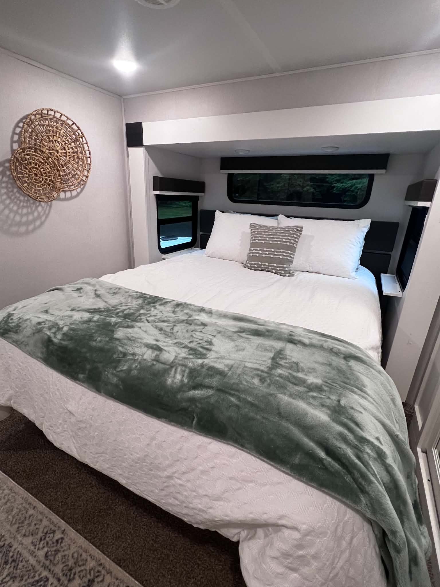 Comfortable RV rental bedroom. White bedding, soft green throw, wall decor, and window views create a relaxing travel space.. Crusader Crusader Fifth Wheel 2021