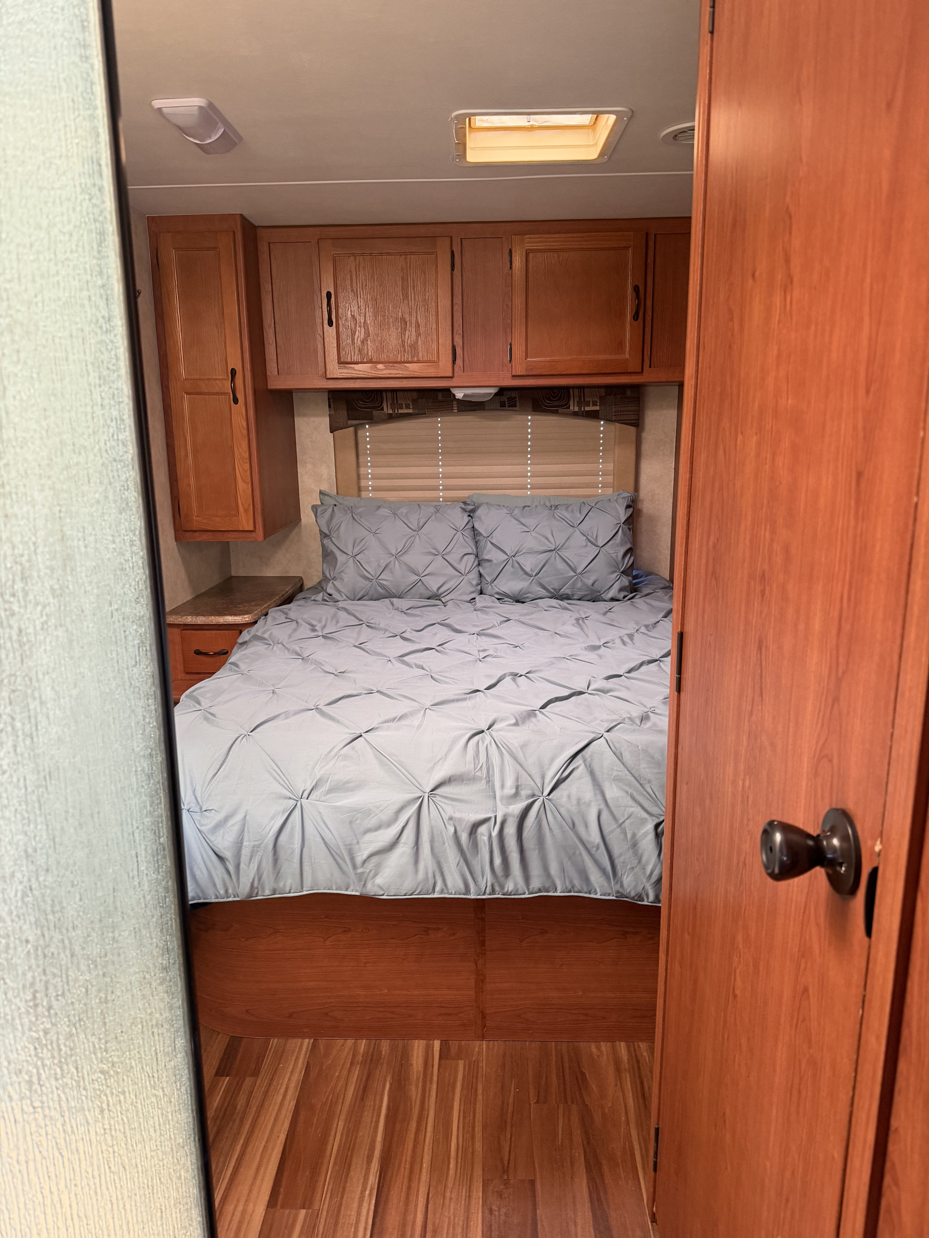 RV rental bedroom interior: a comfortable gray bed, overhead wood cabinets, and a ceiling vent/skylight.. Forest River,Inc Coachman Freelander 2012