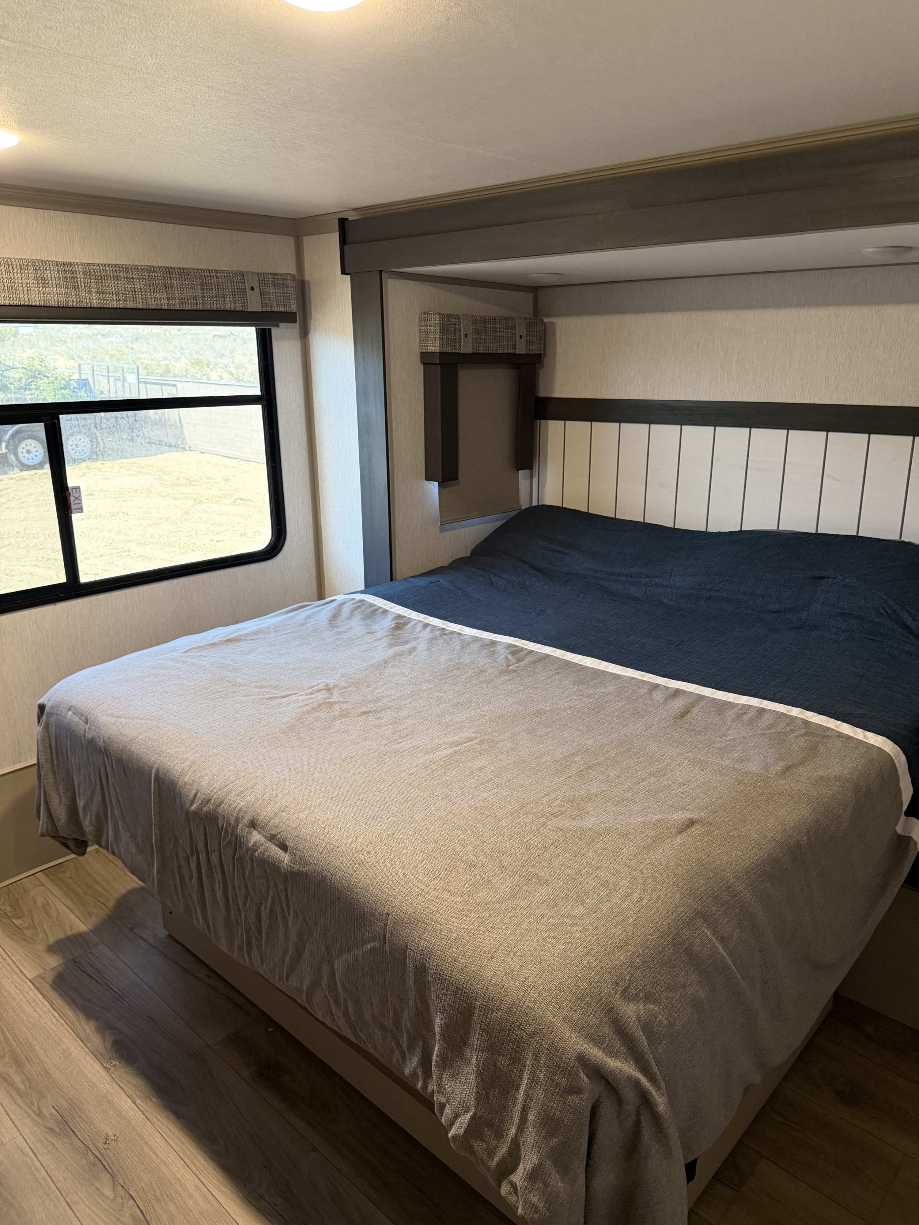 Clean, modern rv rental bedroom featuring a comfortable bed, large window, and wood-look flooring.. Forest River Salem Hemisphere 2023