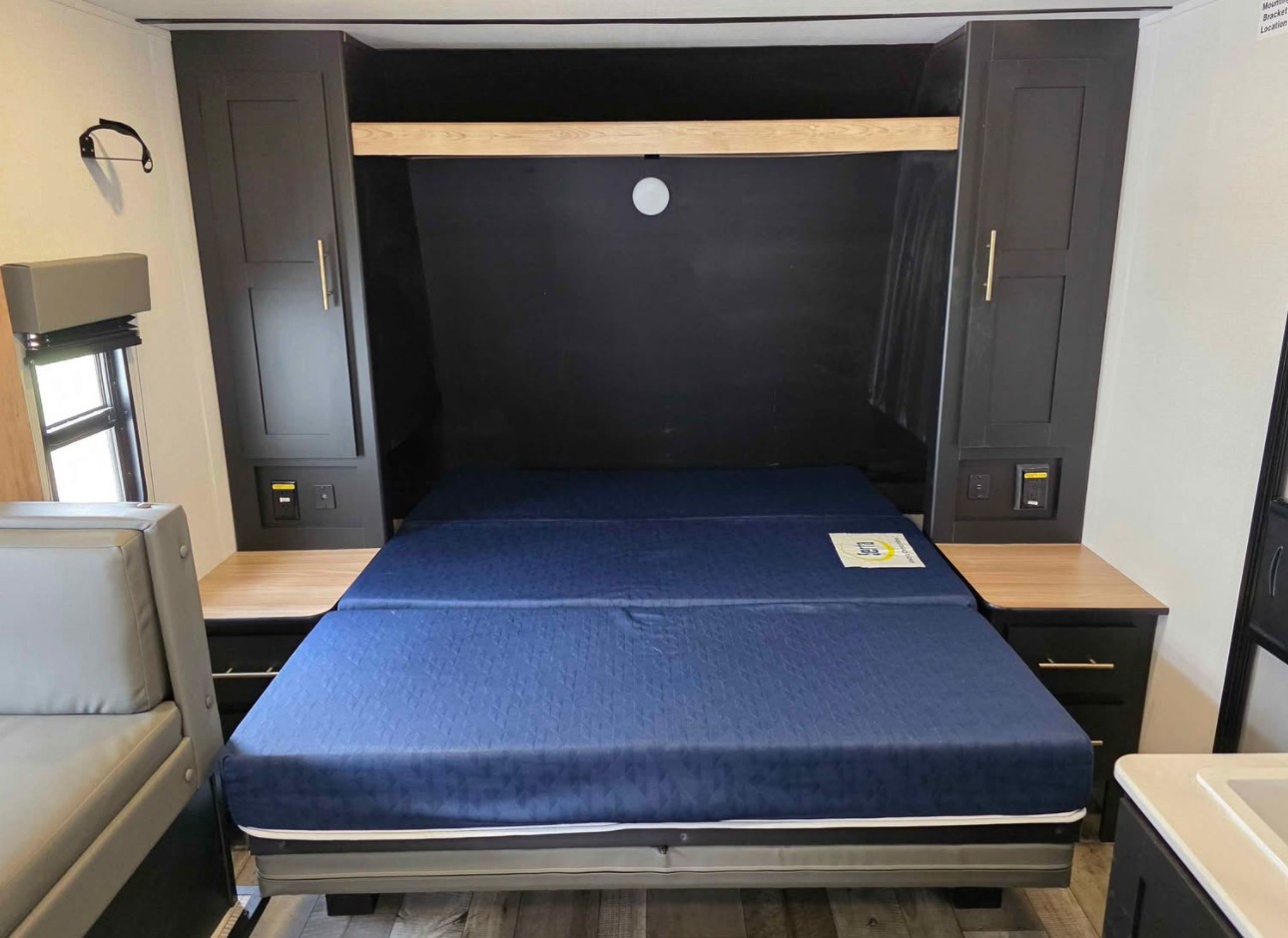 RV rental: This compact bedroom features a blue fold-down mattress, integrated black cabinets, and side tables.. Keystone RV Springdale 2023