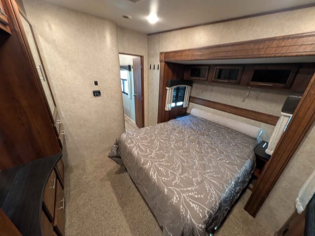 Cozy RV rental bedroom interior, featuring a comfortable bed, ample storage, and a doorway, ideal for your next adventure.. Jayco Eagle 2018