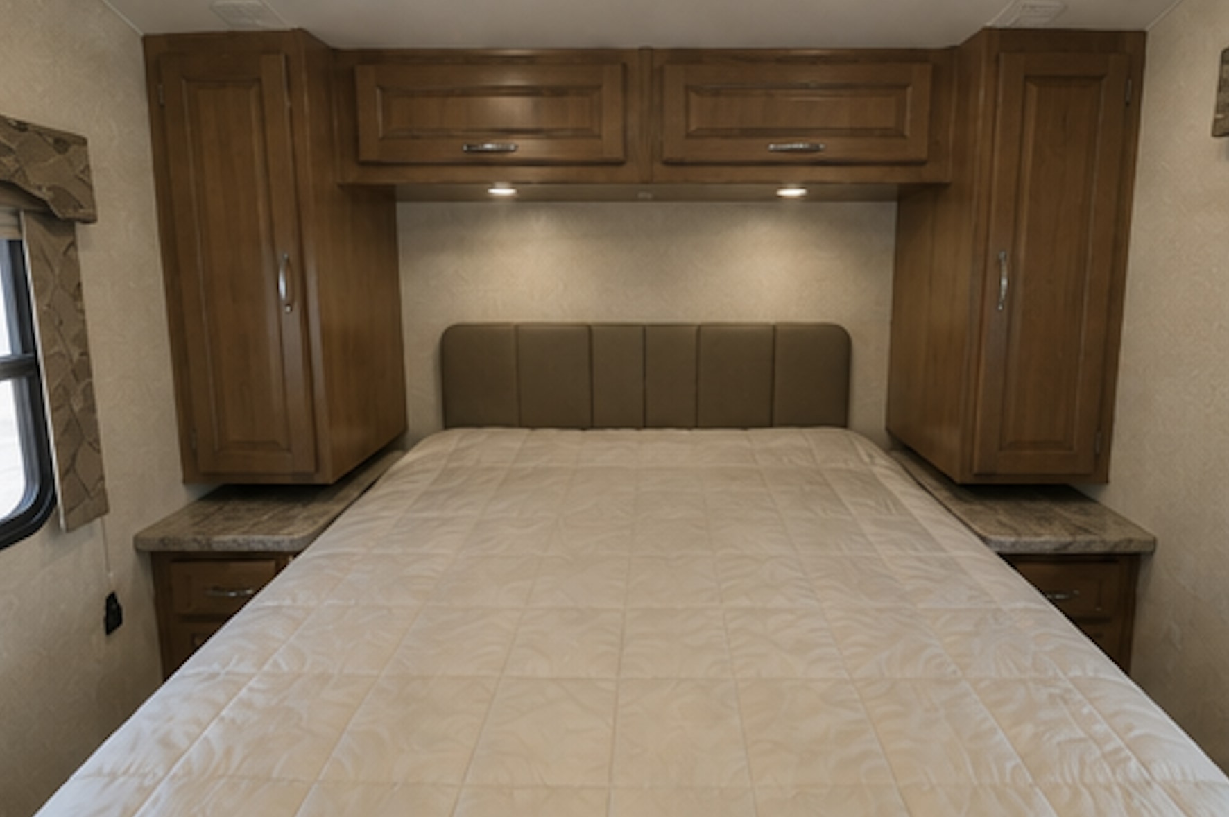 Cozy RV rental bedroom features a comfy bed with padded headboard, overhead storage, and bedside cabinets.. Jayco Melbourne 2017